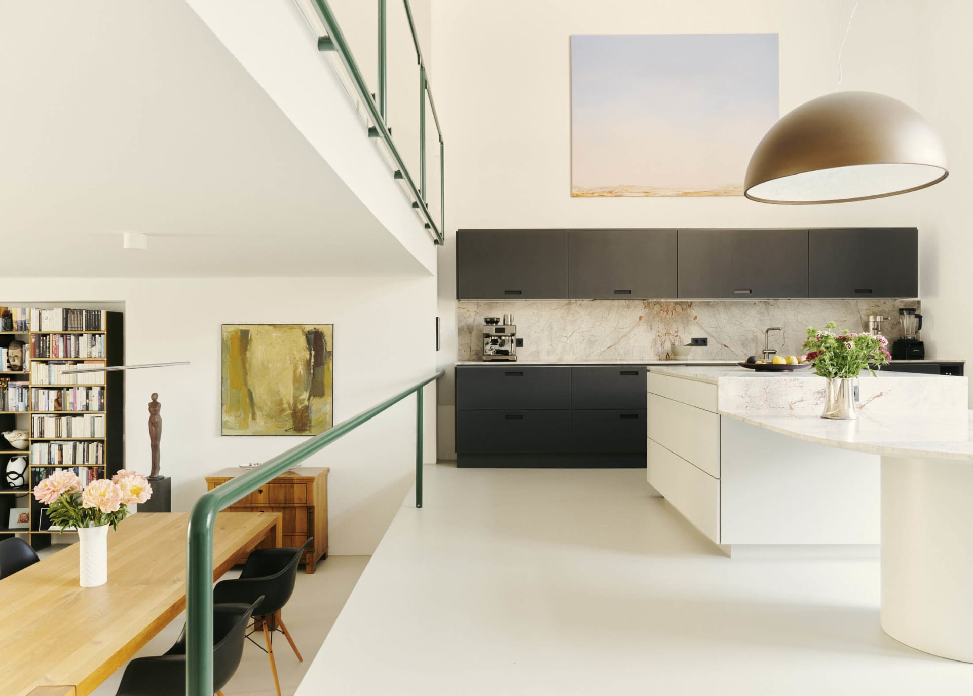 A modern kitchen with minimalist design, featuring black cabinets, marble countertops, and a large marble island.