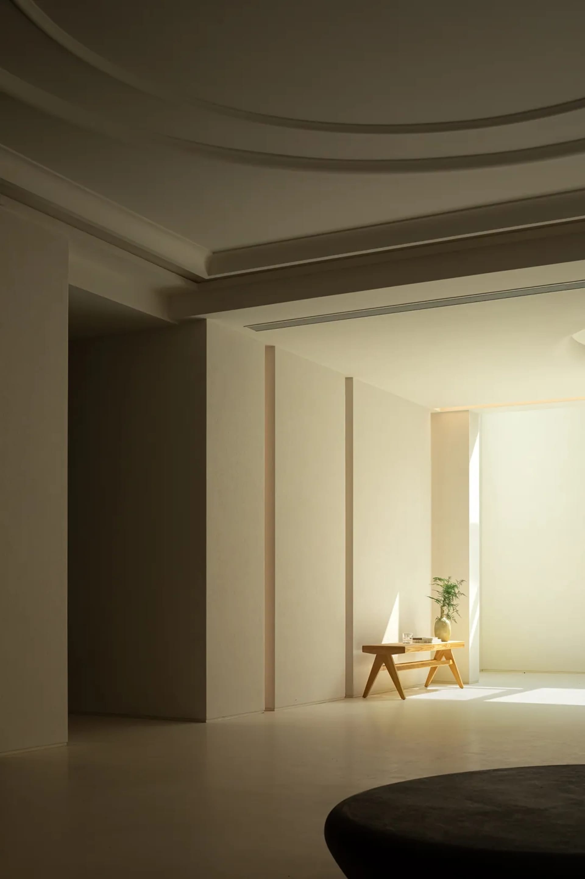 Minimalist living room with natural wood furniture and a sunlit corner.