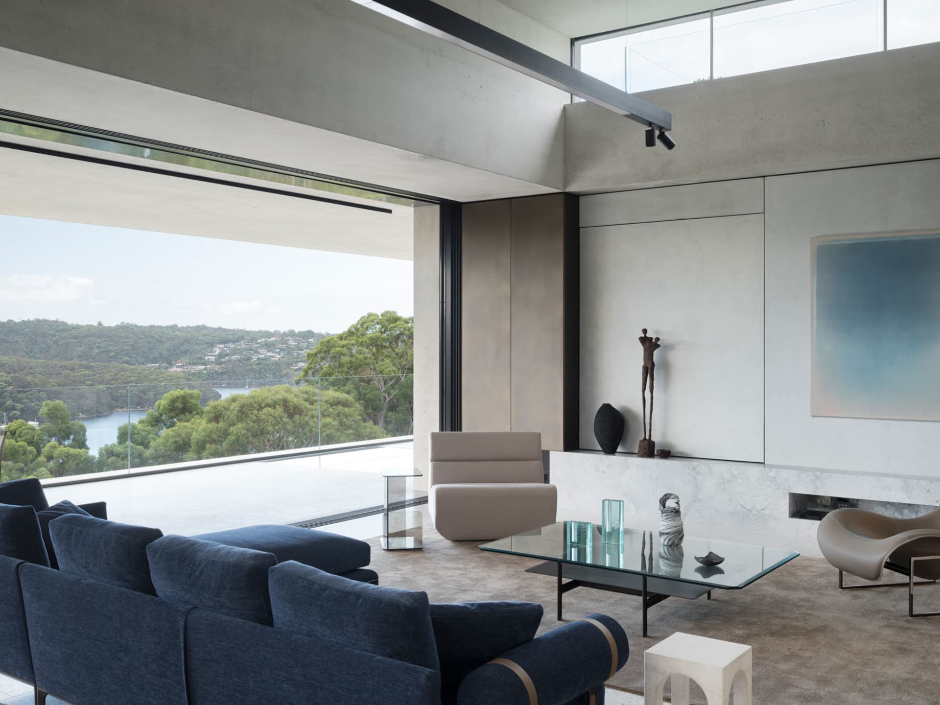 Modern living room featuring glass and concrete materials with a view of the natural landscape.