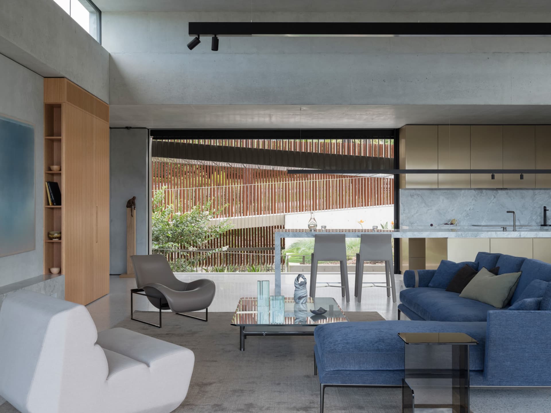 Modern living room featuring a concrete floor and walls, with a blue sofa and white accent chair.