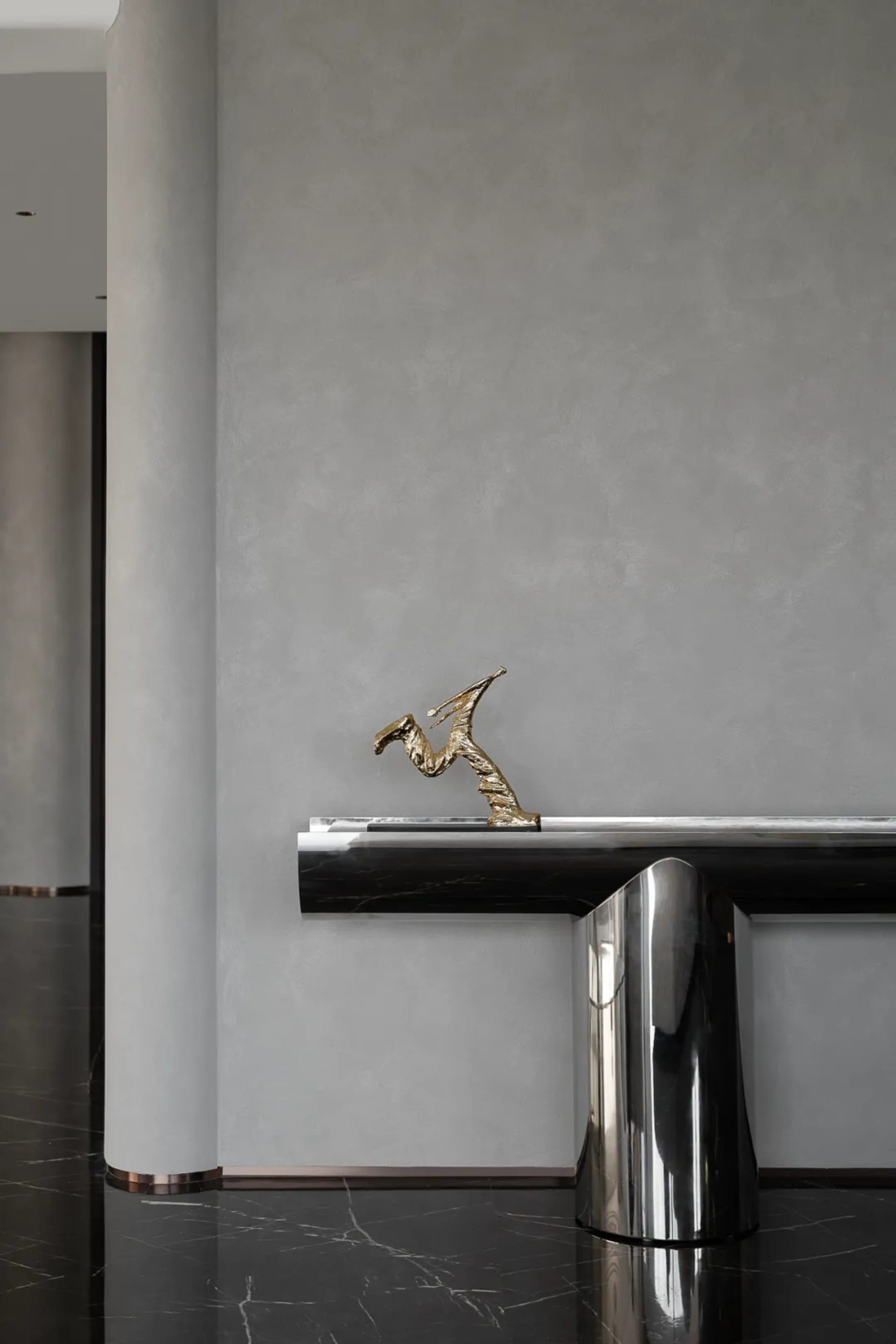 A sleek, modern console table with a brass sculpture in a minimalist interior setting.
