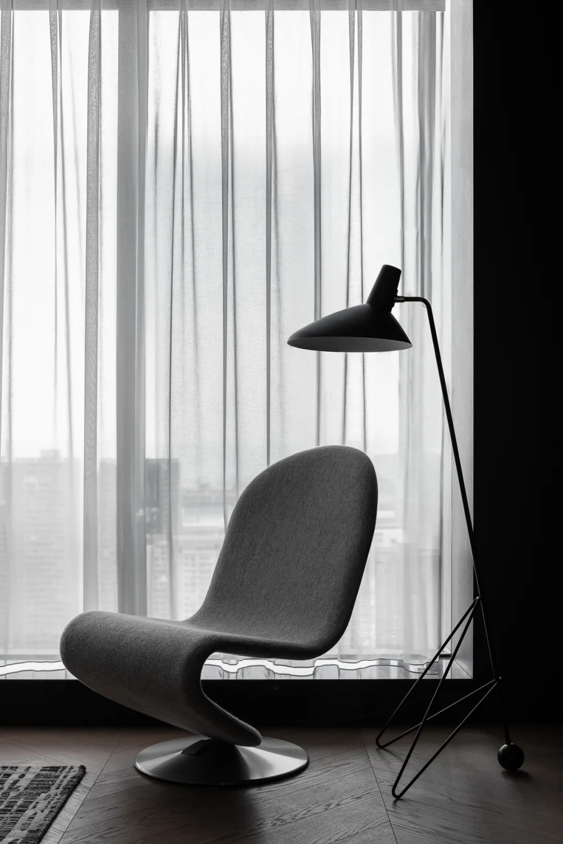 A modern living room featuring a fabric armchair and a minimalist floor lamp.