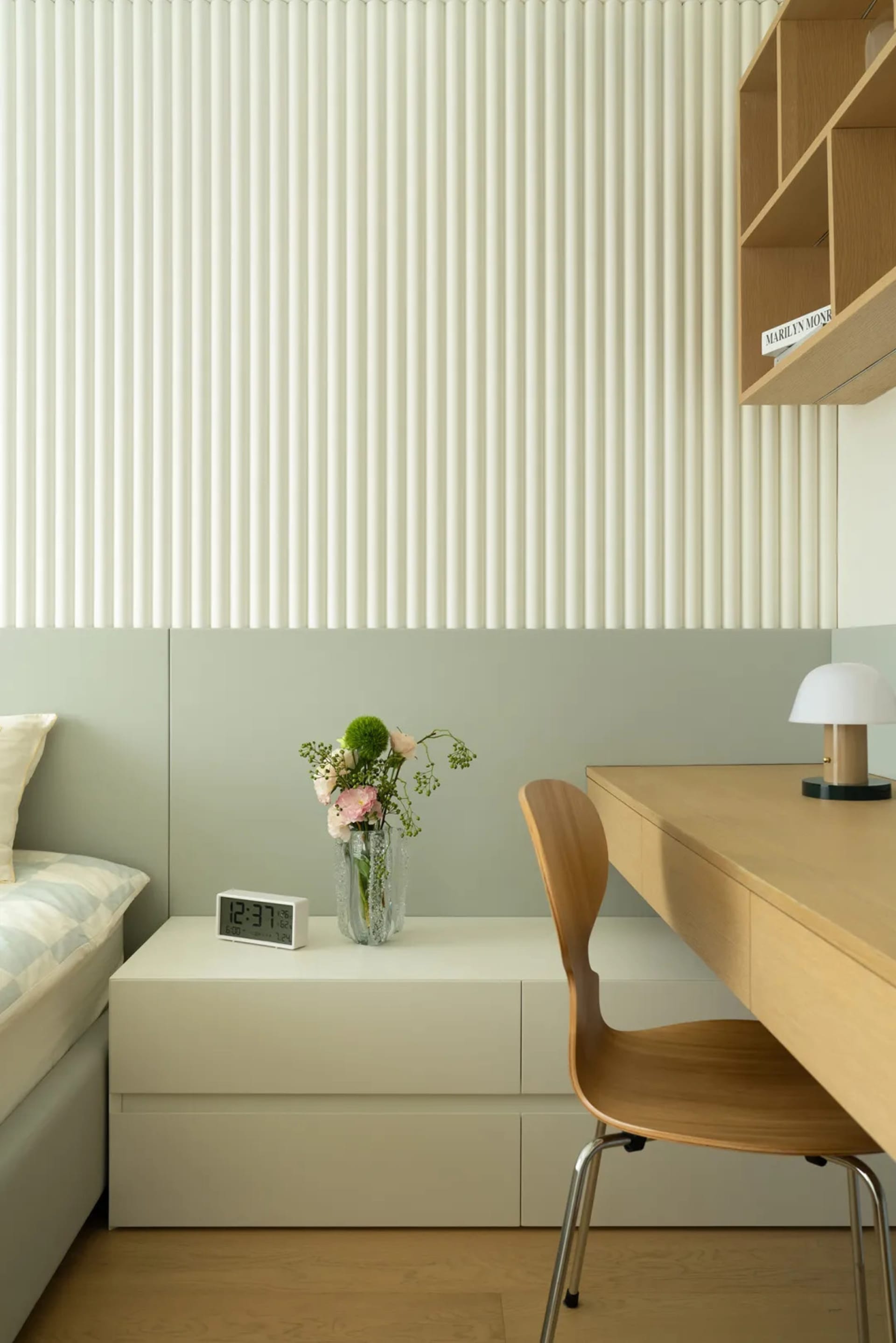 A modern bedroom featuring a wooden desk and chair against a wall with vertical lines.
