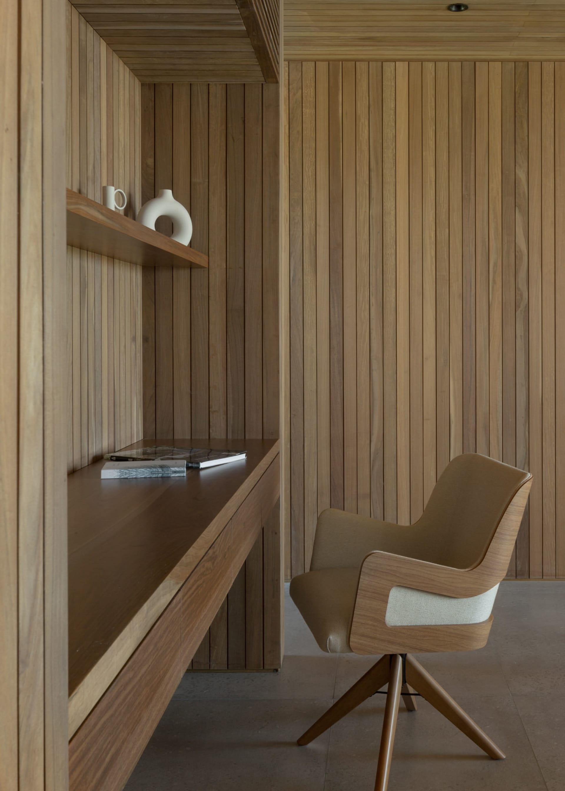 A modern minimalist home office with wooden elements, featuring a built-in desk and comfortable seating.