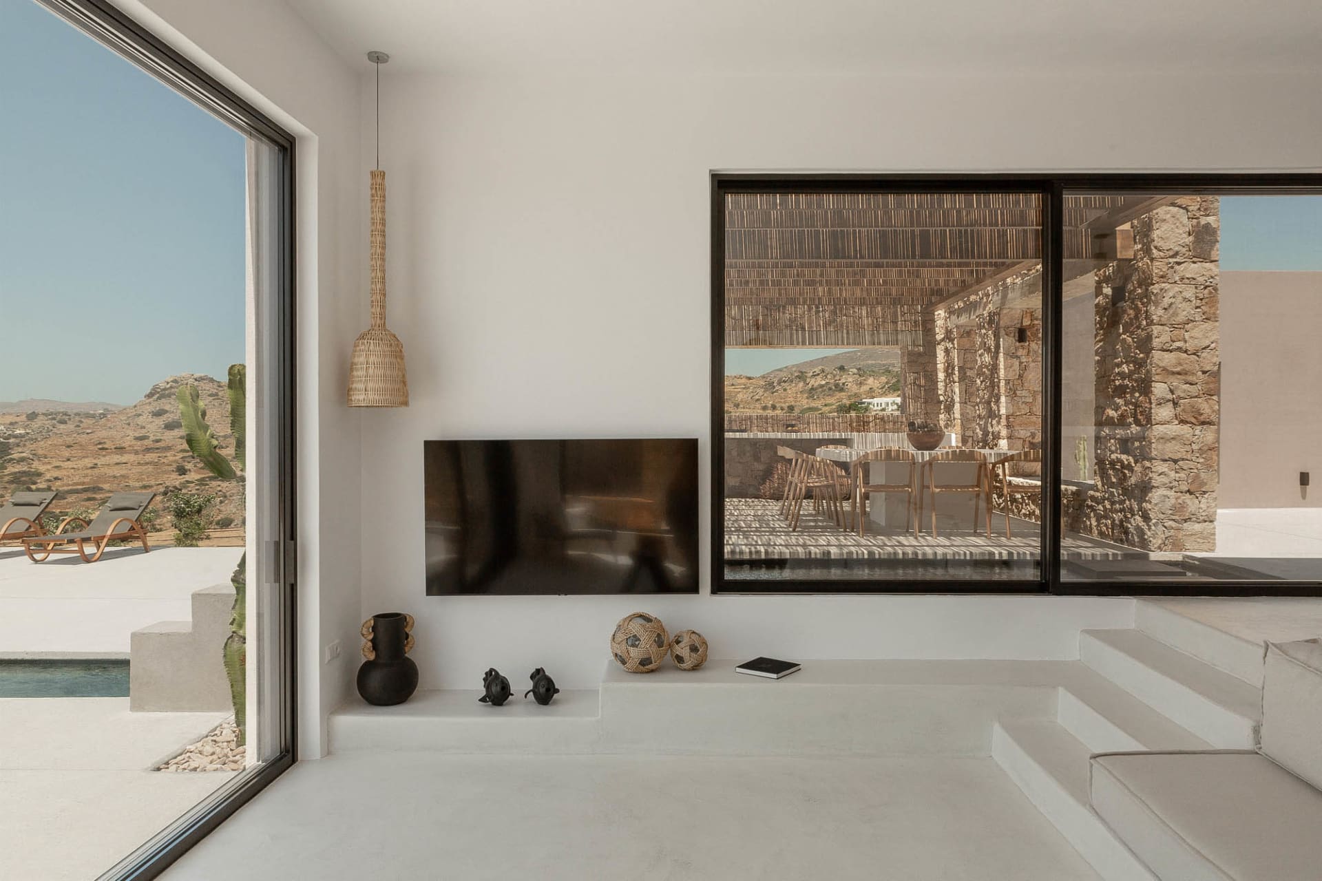 A minimalist residential interior with concrete flooring, glass walls, and a terrazzo dining area.