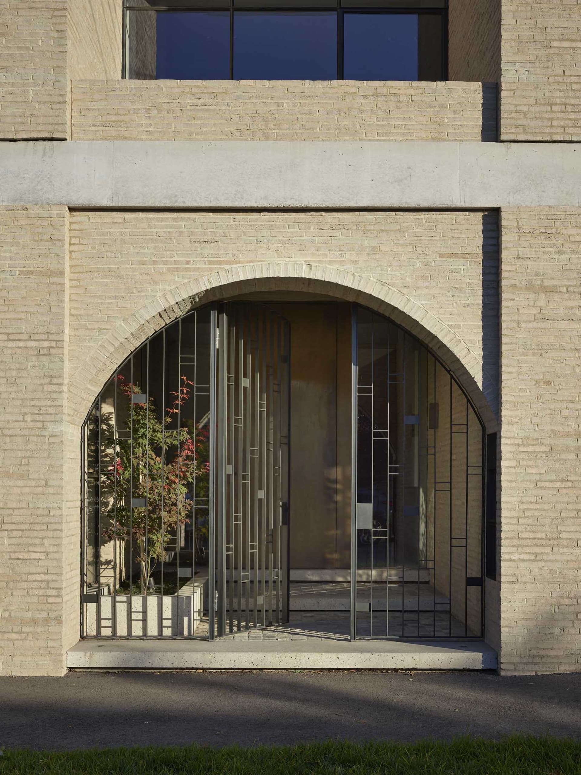 Modern entrance with an arched concrete gate and a glass door in the background.