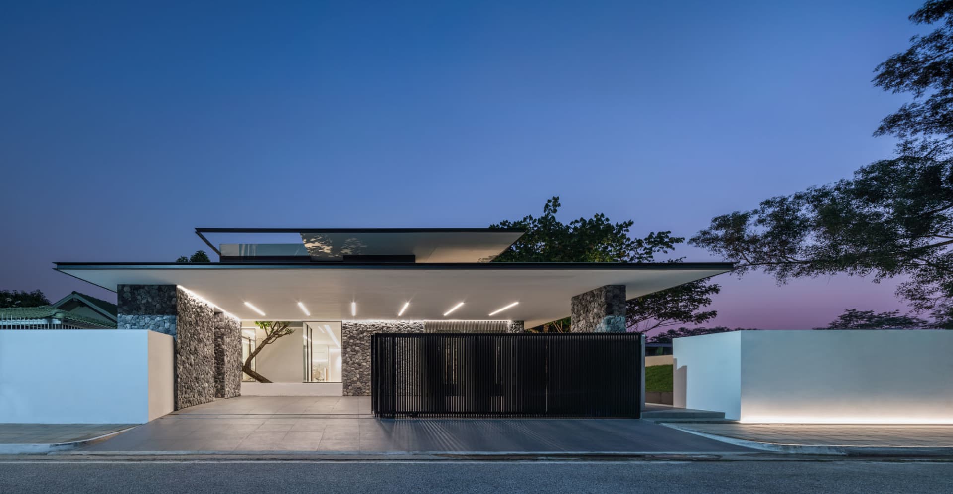 A modern house with a concrete exterior, glass rooftop, and stone accents.