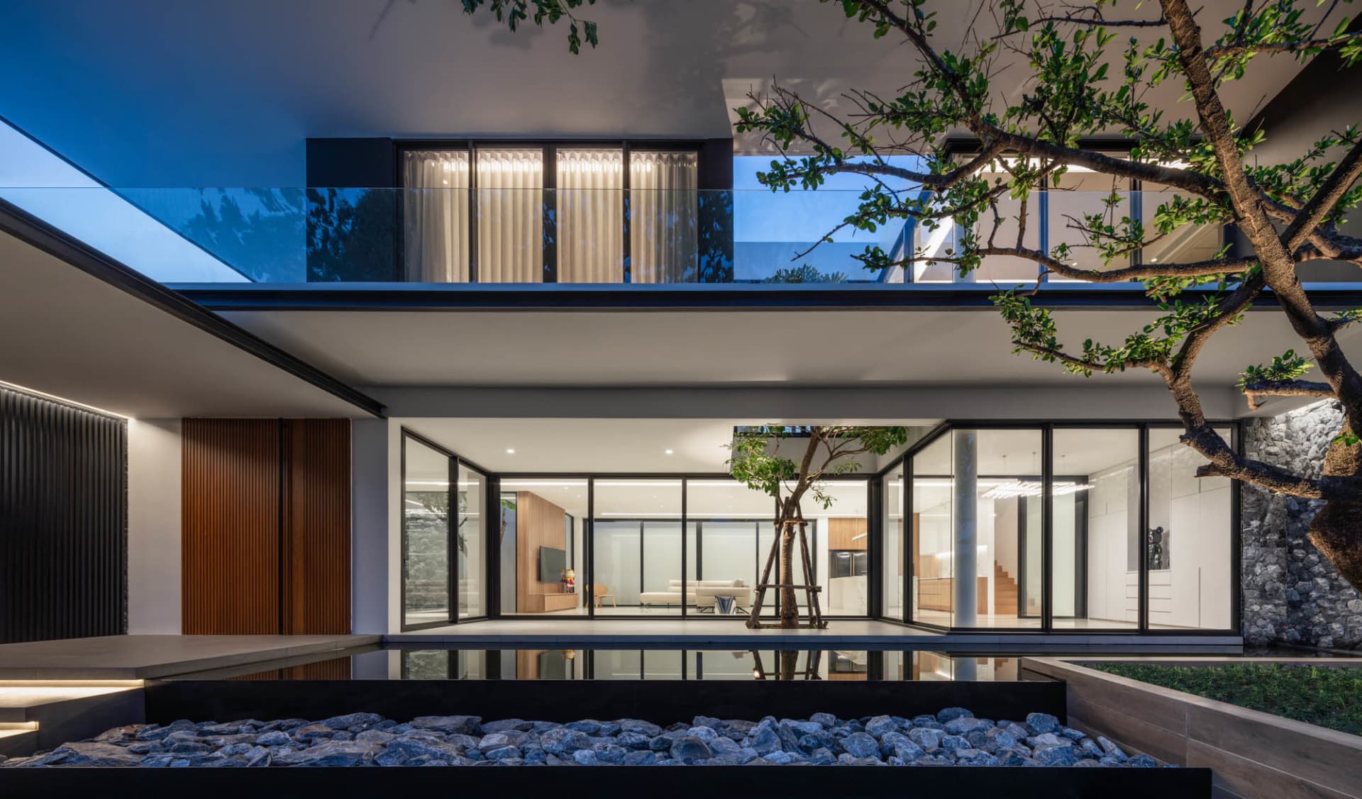 Modern residential interior with glass walls, wood flooring, and concrete patio.