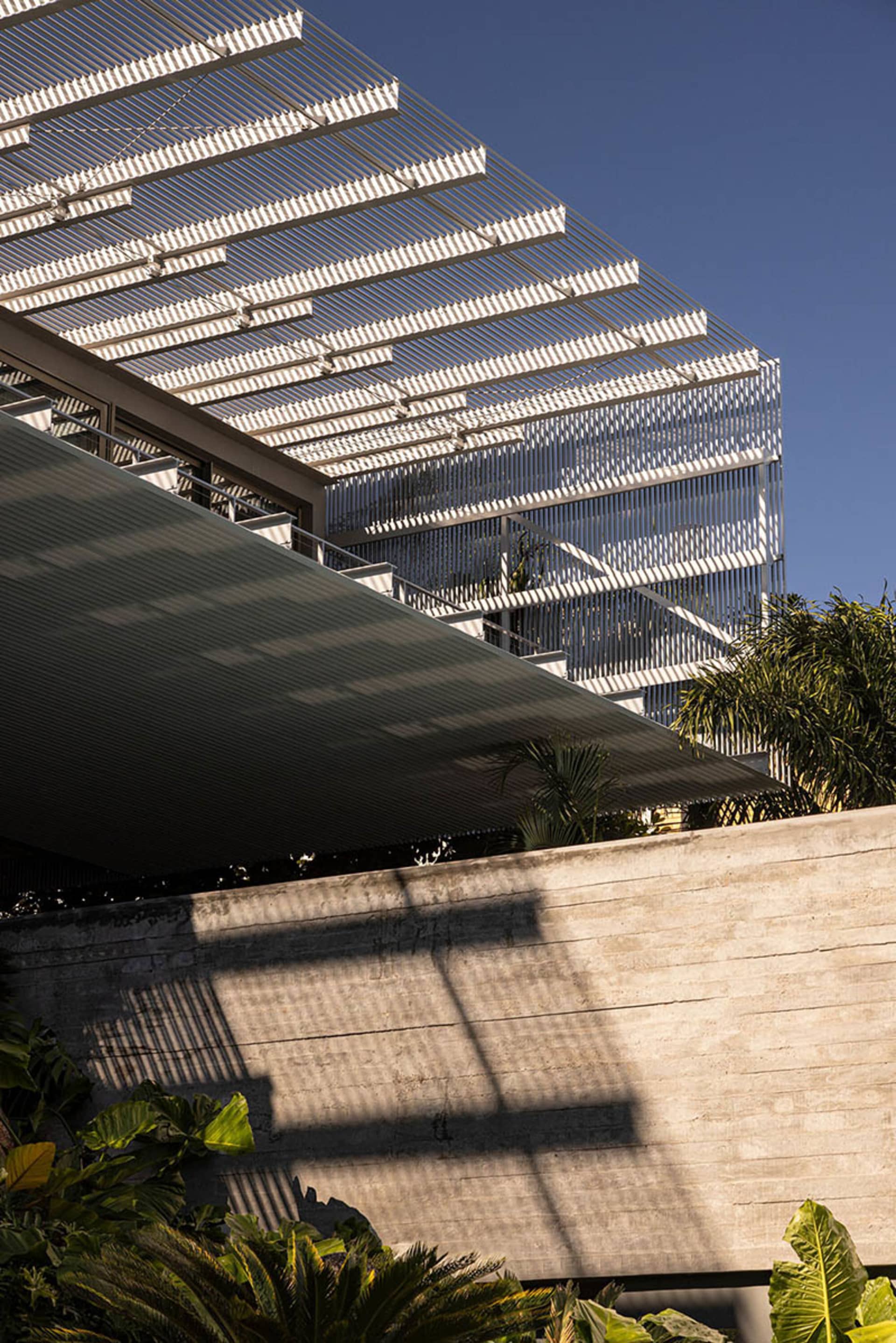 Modern exterior with metal pergola and concrete wall.