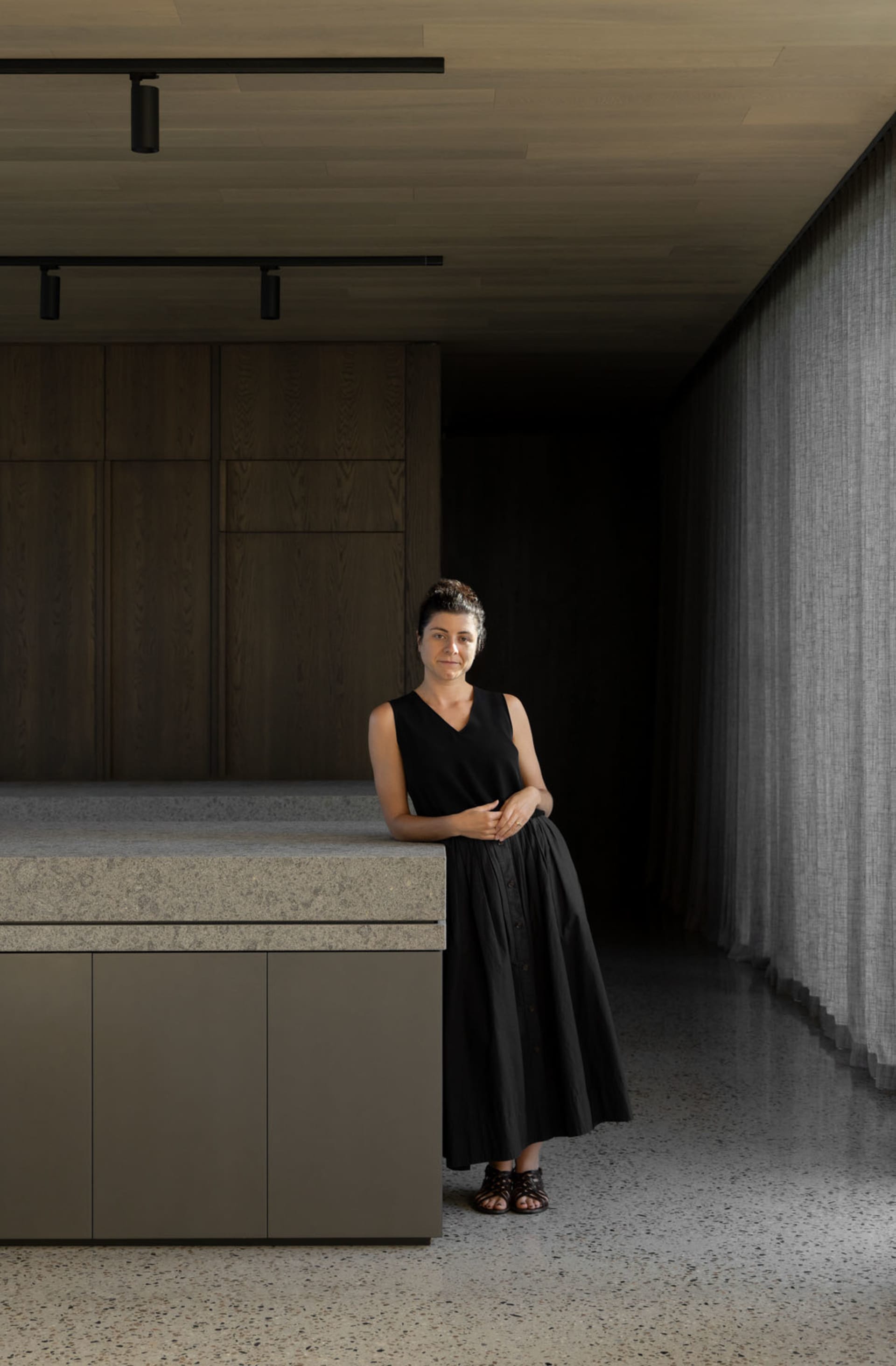 A woman standing in a modern office space with concrete flooring and minimalist decor.