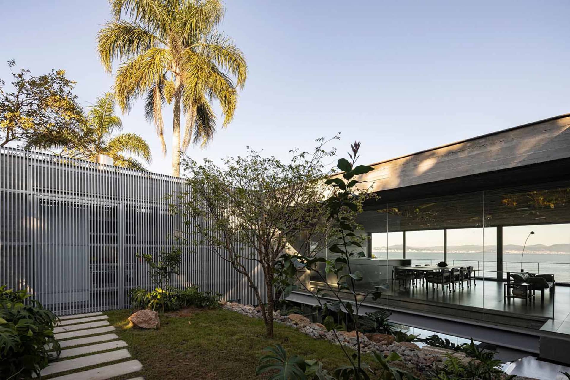 Modern residential interior featuring metal-clad structure, glass windows, and concrete ground with outdoor dining area and s