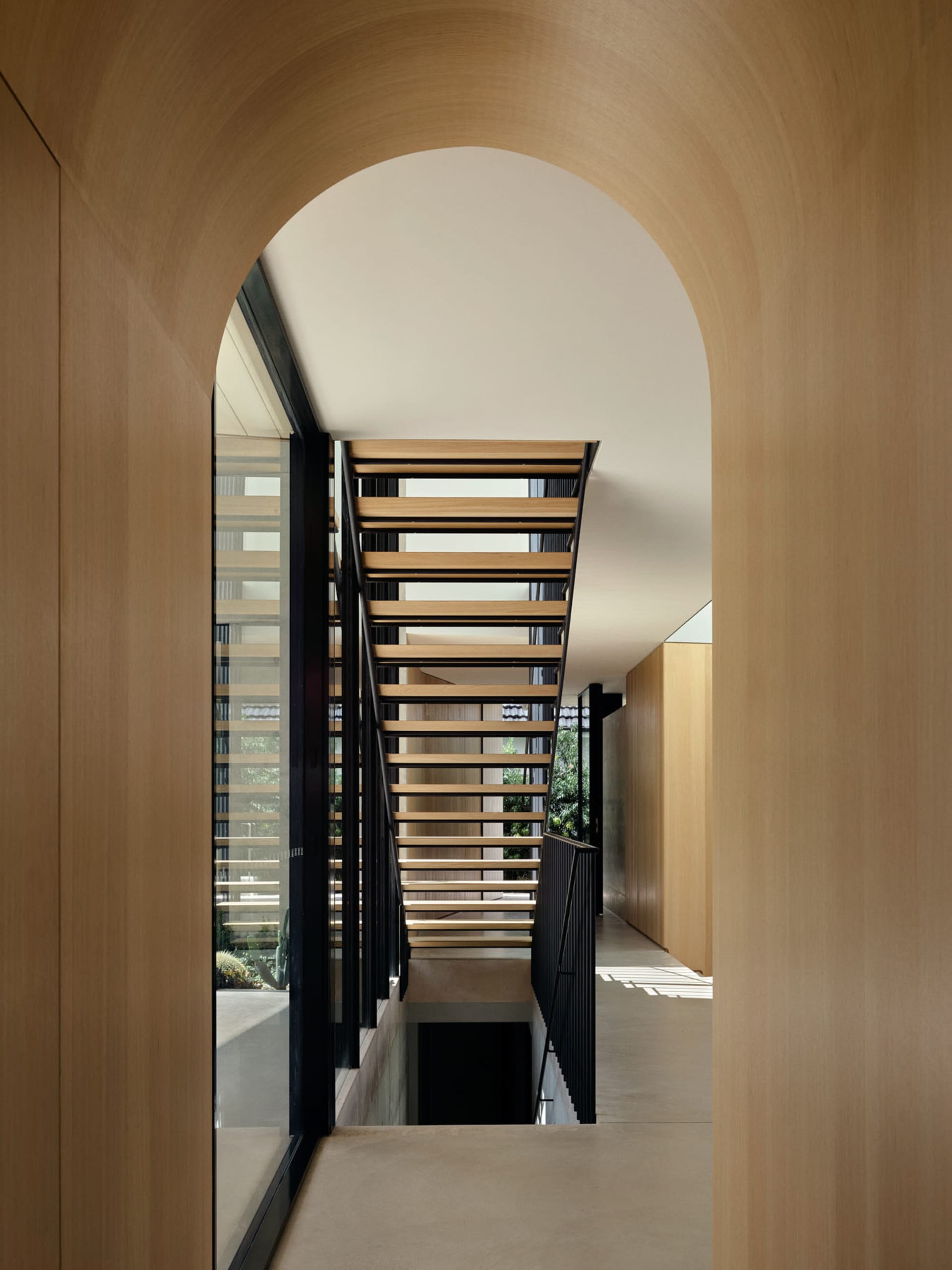 Architectural interior design featuring a modern wooden staircase with black railings and wooden flooring.