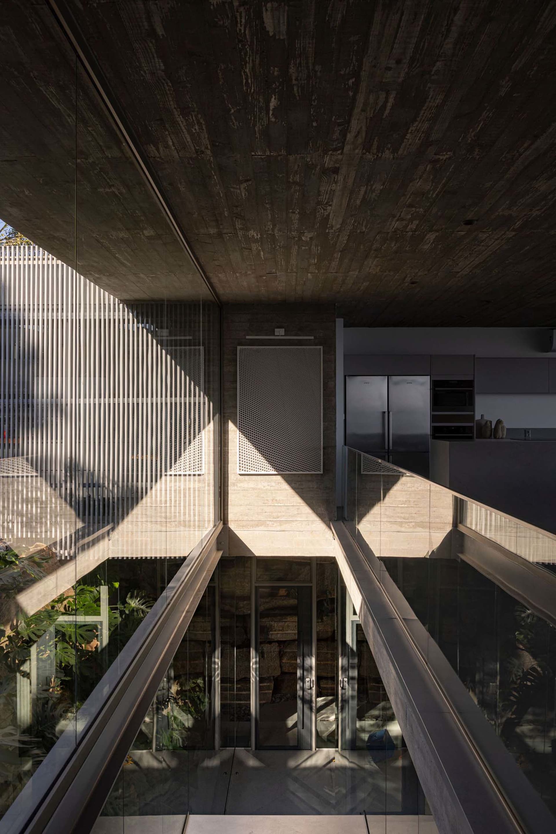 A futuristic industrial-style residential kitchen designed with concrete and glass materials, featuring a sleek, modern aesth
