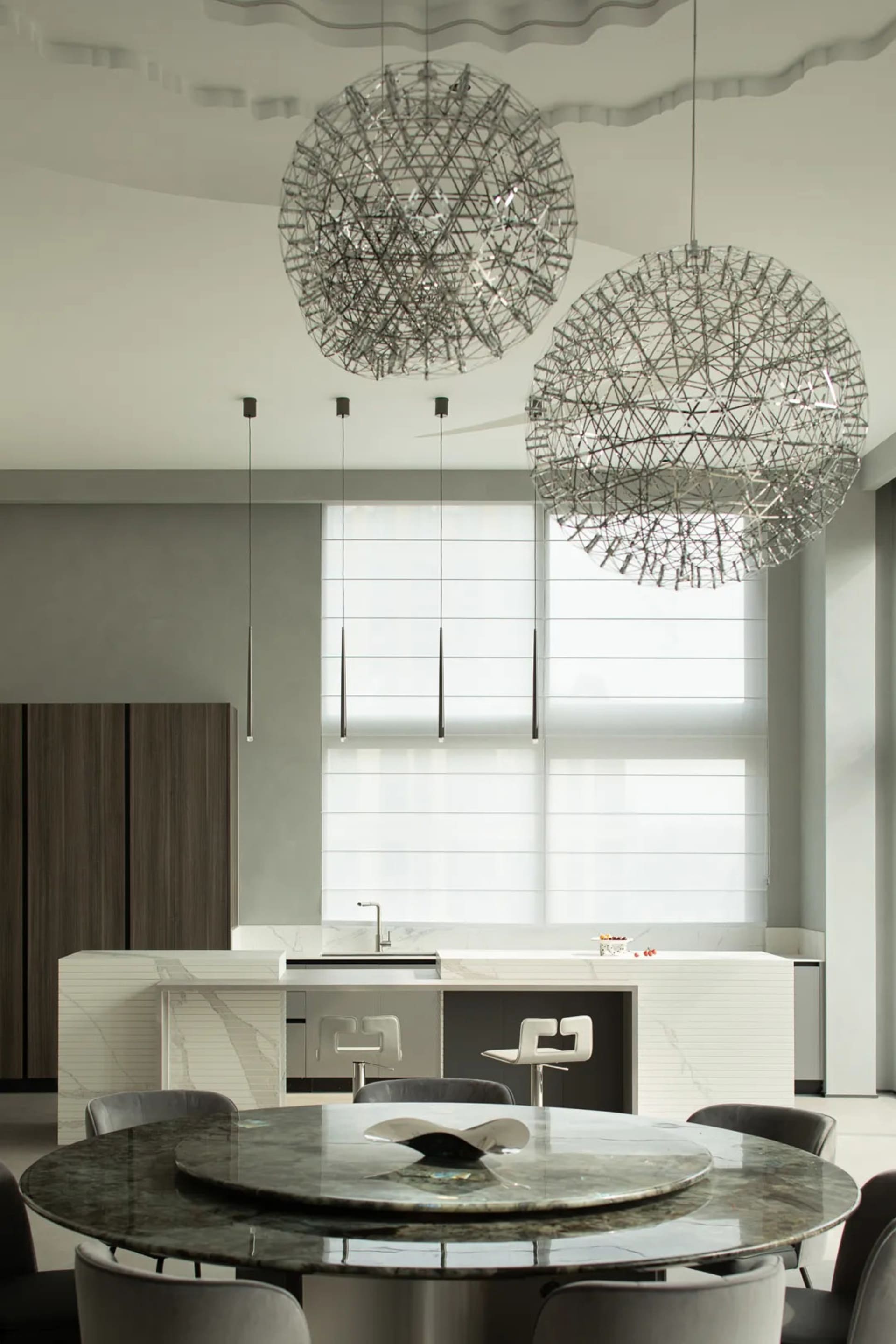 Modern kitchen interior with marble island, white walls, and large pendant lights.
