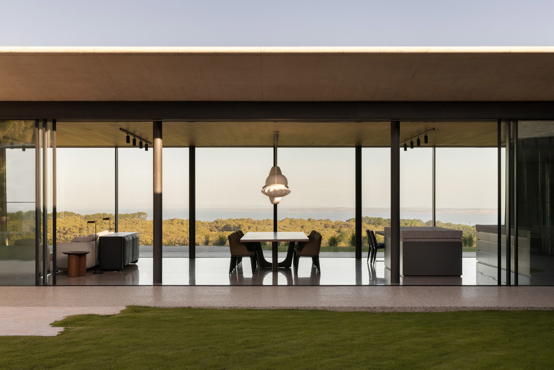 A modern residential interior featuring glass walls and concrete flooring.