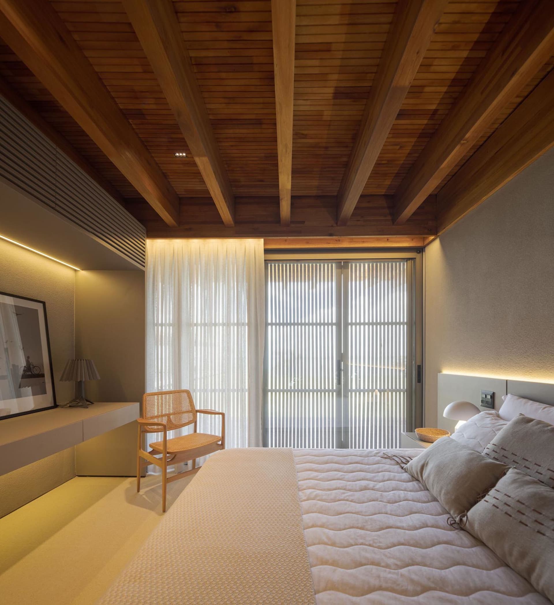 Modern minimalist bedroom featuring a wooden ceiling and soft textiles.