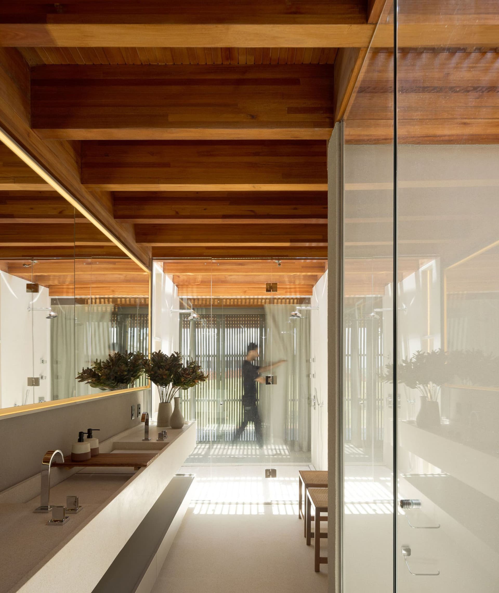 Modern bathroom with wooden beams, glass walls, and a minimalist design.
