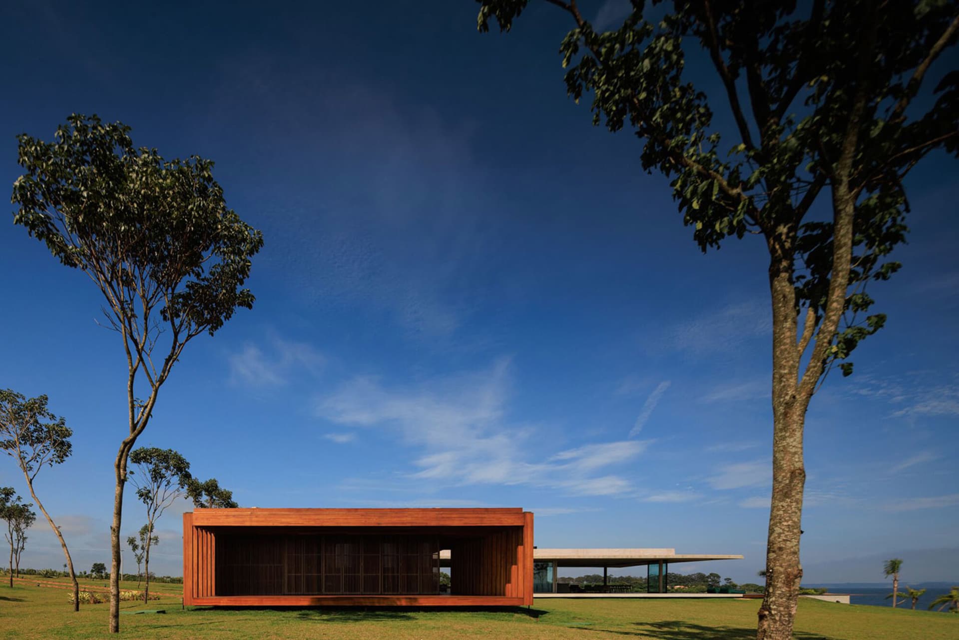 A minimalist residential exterior with wooden materials and a glass wall