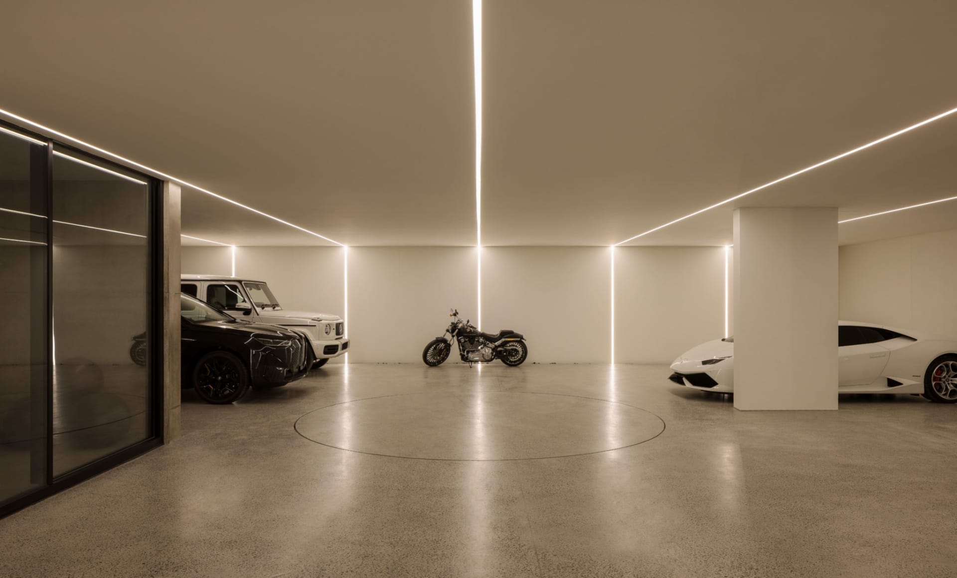Minimalist style garage with circular concrete floor, concrete walls, and modern vehicles.