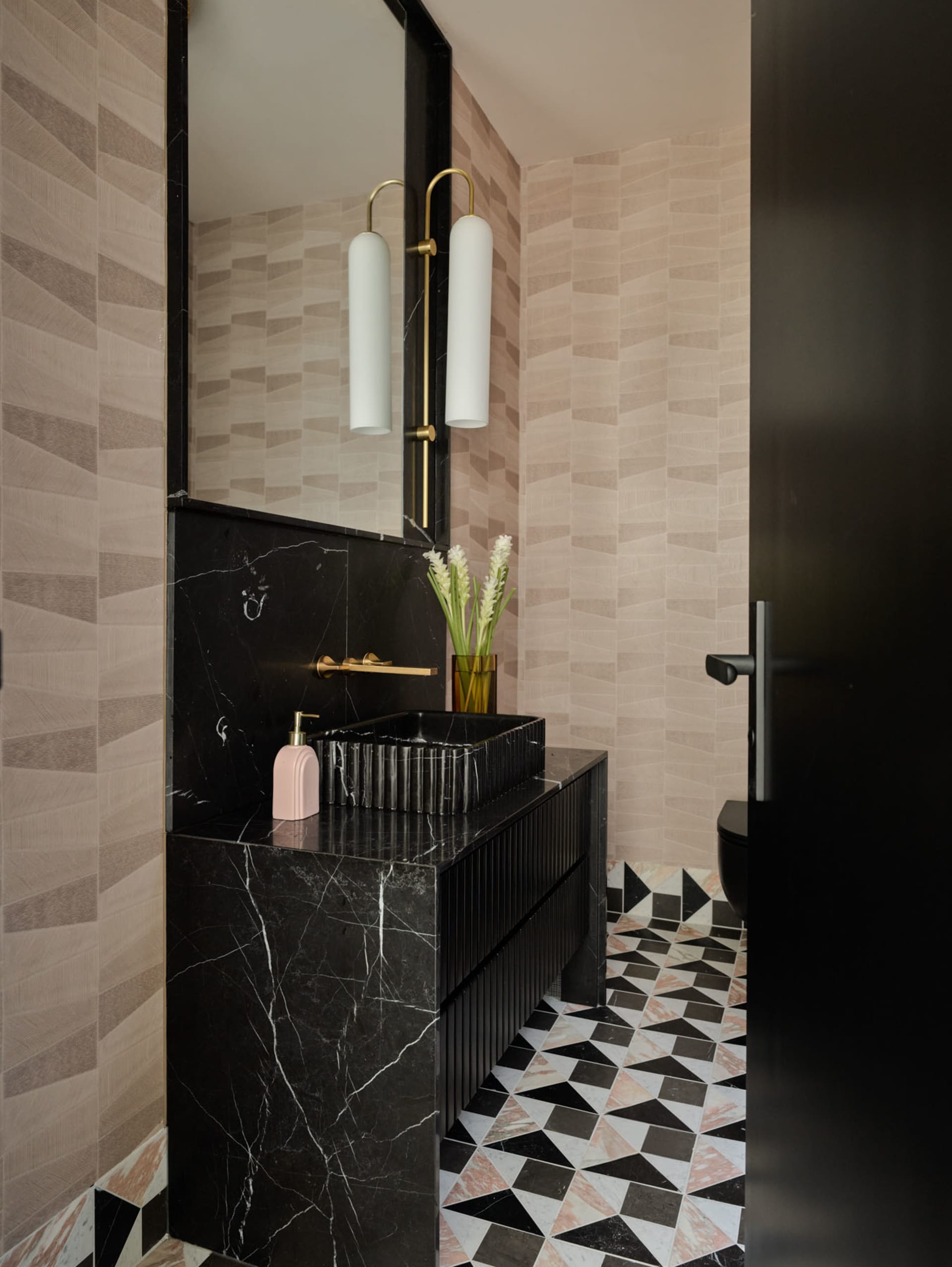 Modern bathroom with black marble sink, geometric floor tiles, and beige textured walls.