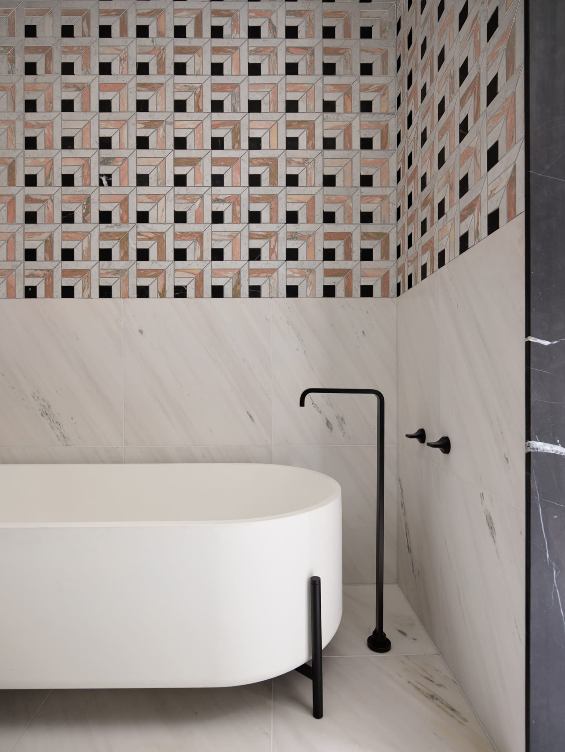 Modern bathroom with white marble tub and geometric tile pattern.