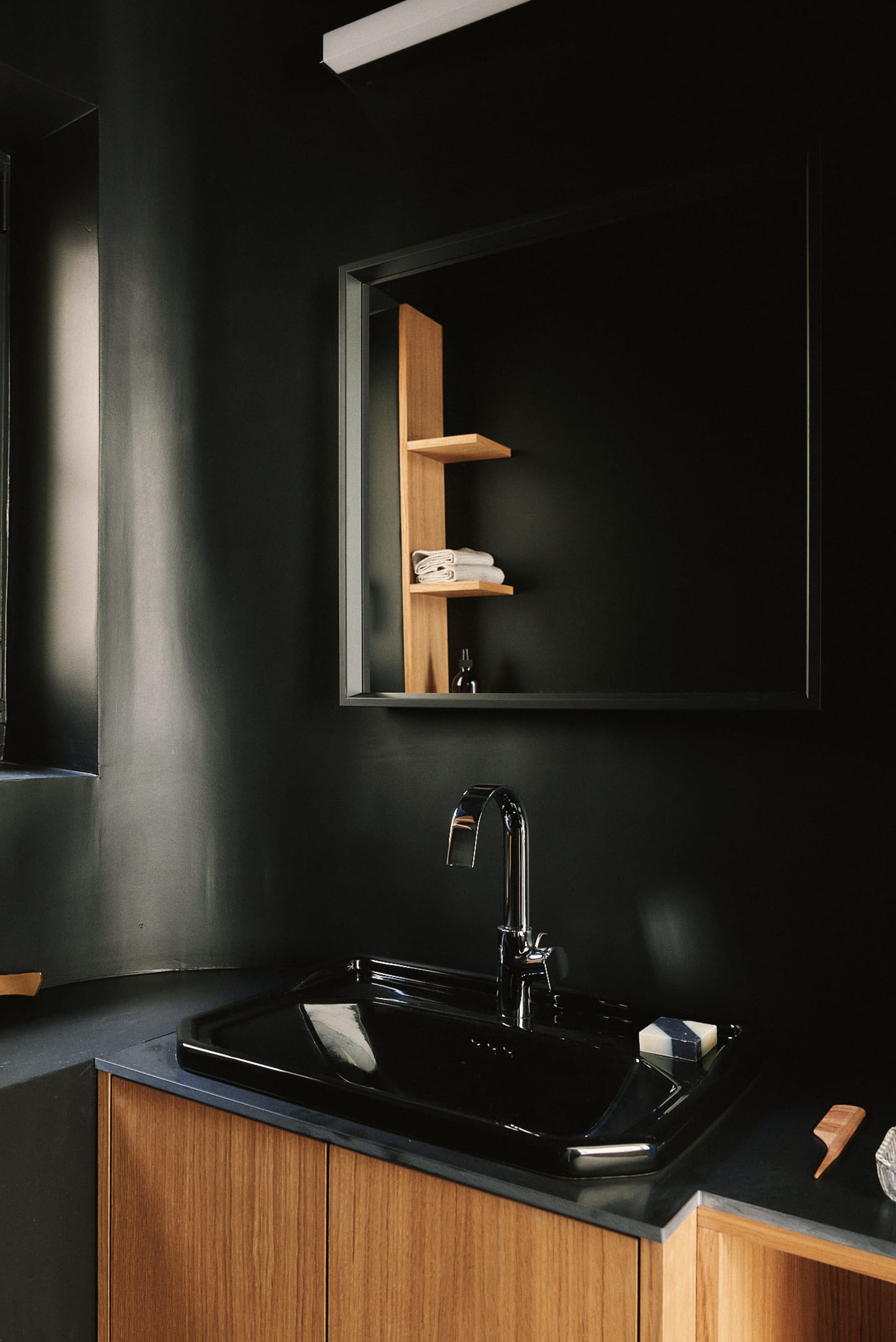 Modern black bathroom with a sleek black sink and wooden cabinets