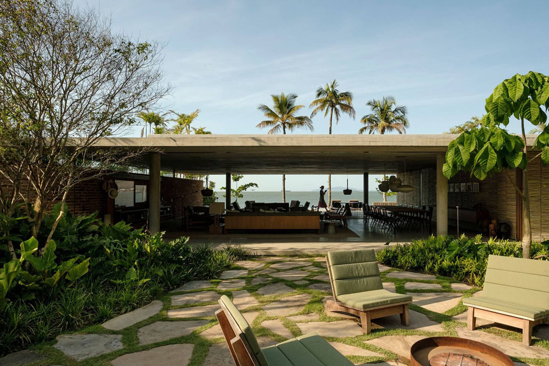 A modern residential patio featuring stone floors, wooden furniture, and concrete structures.