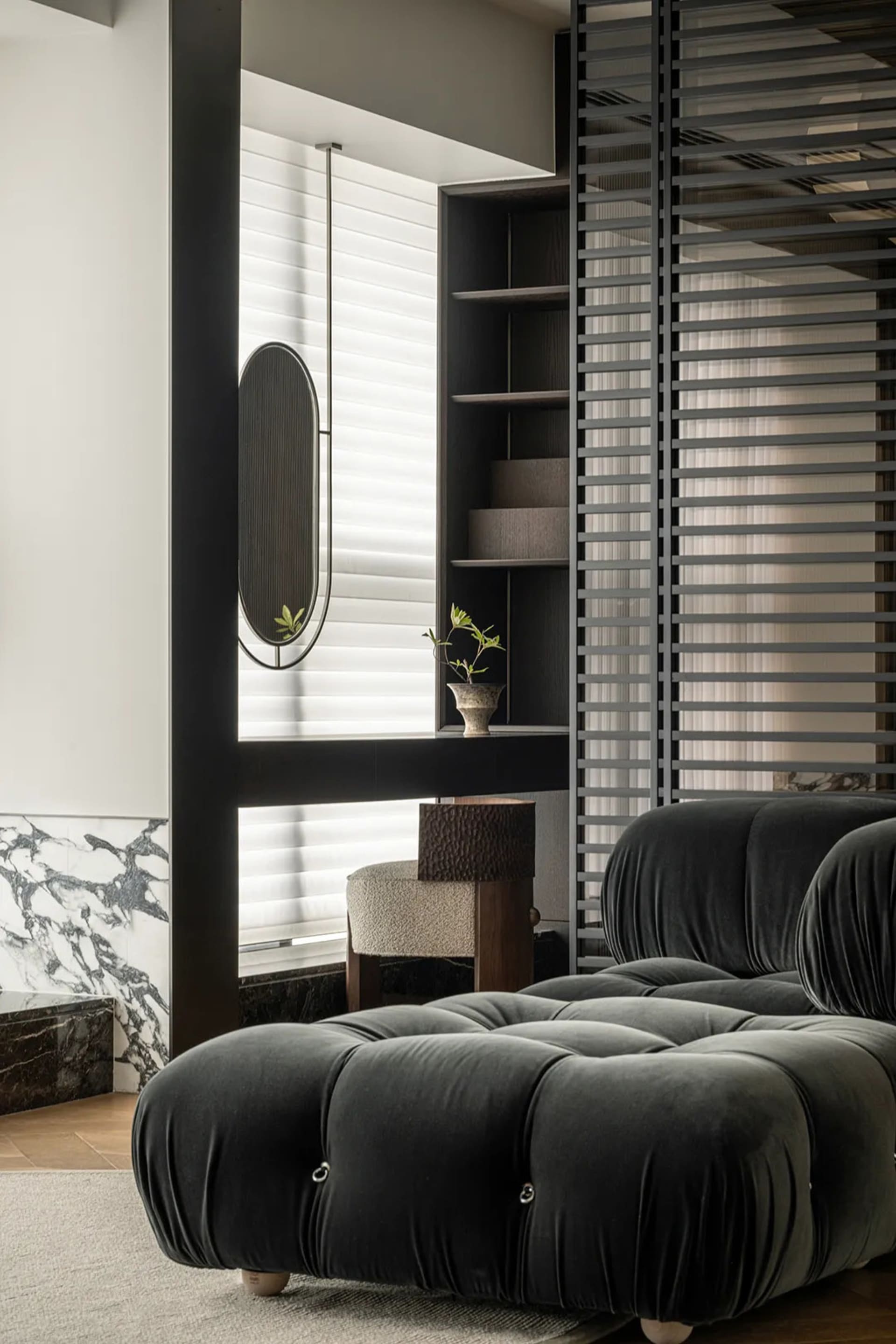 Modern living room featuring plush, tufted black velvet furniture, a round table, and minimalist decor.