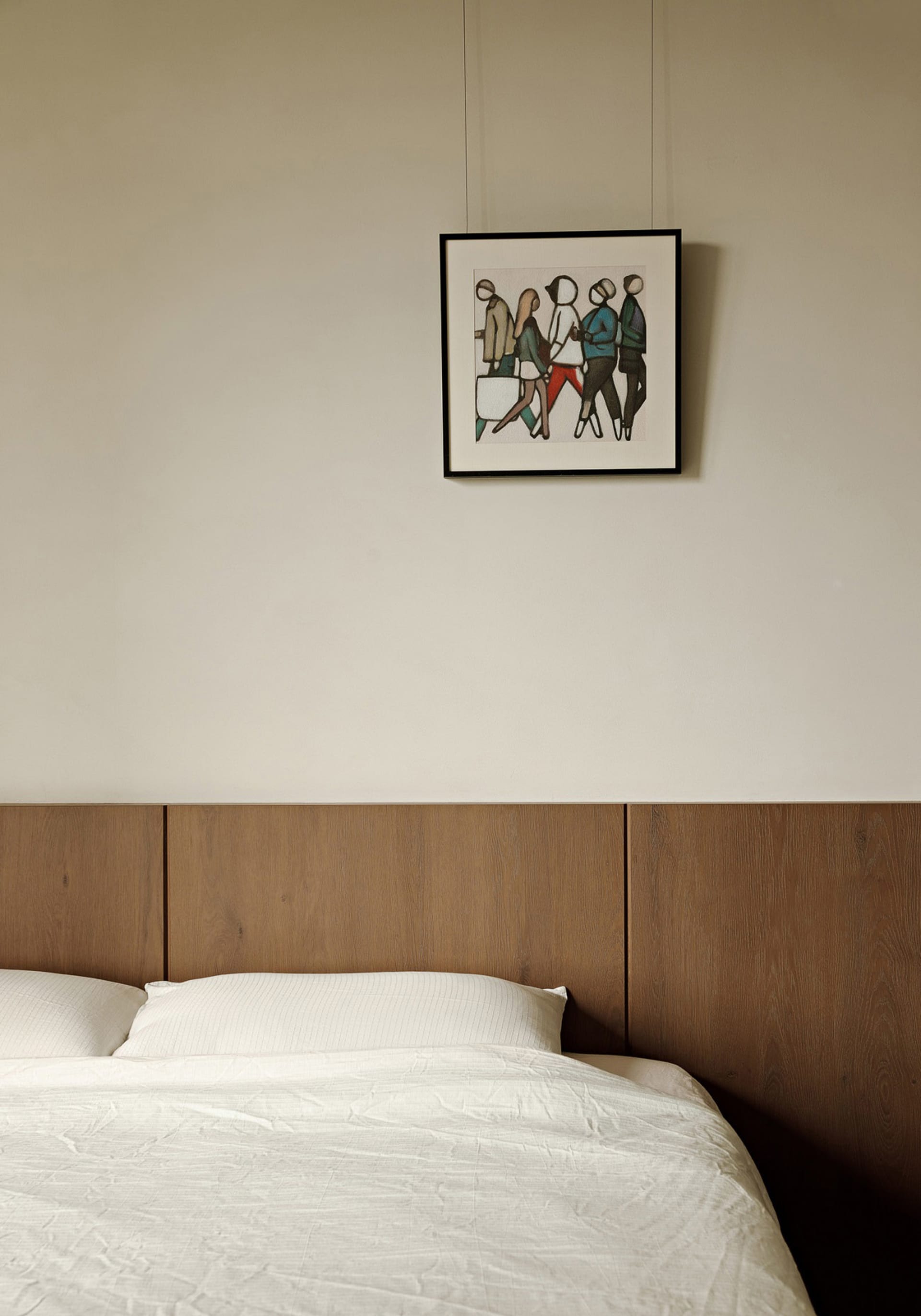 A minimalist bedroom featuring a wood headboard and white bedding.
