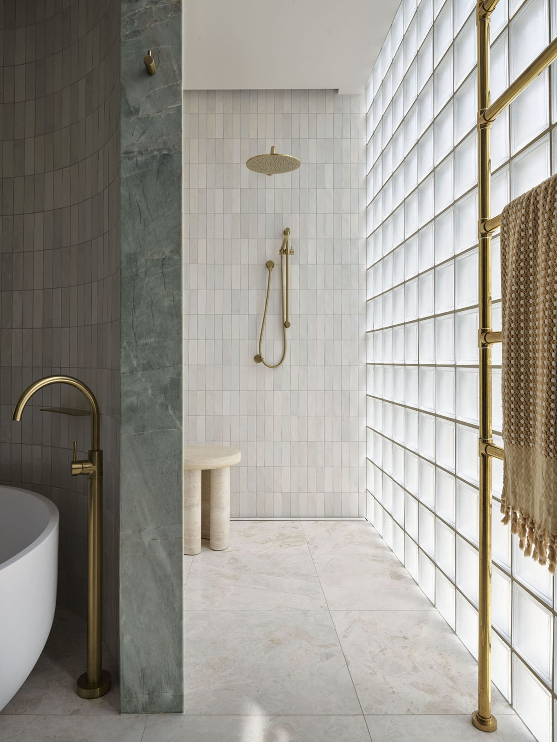 Contemporary bathroom with tiled walls, freestanding tub, and gold fixtures.