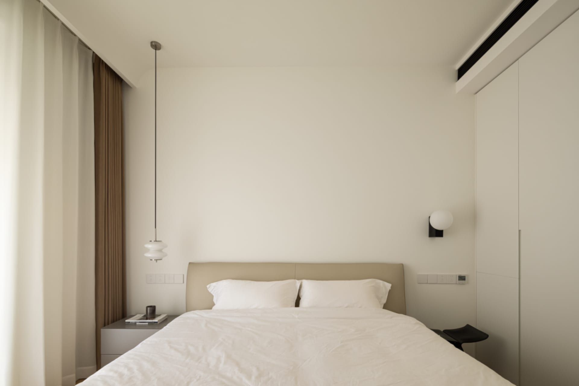 Modern minimalist bedroom with a bed, nightstand, and white walls.