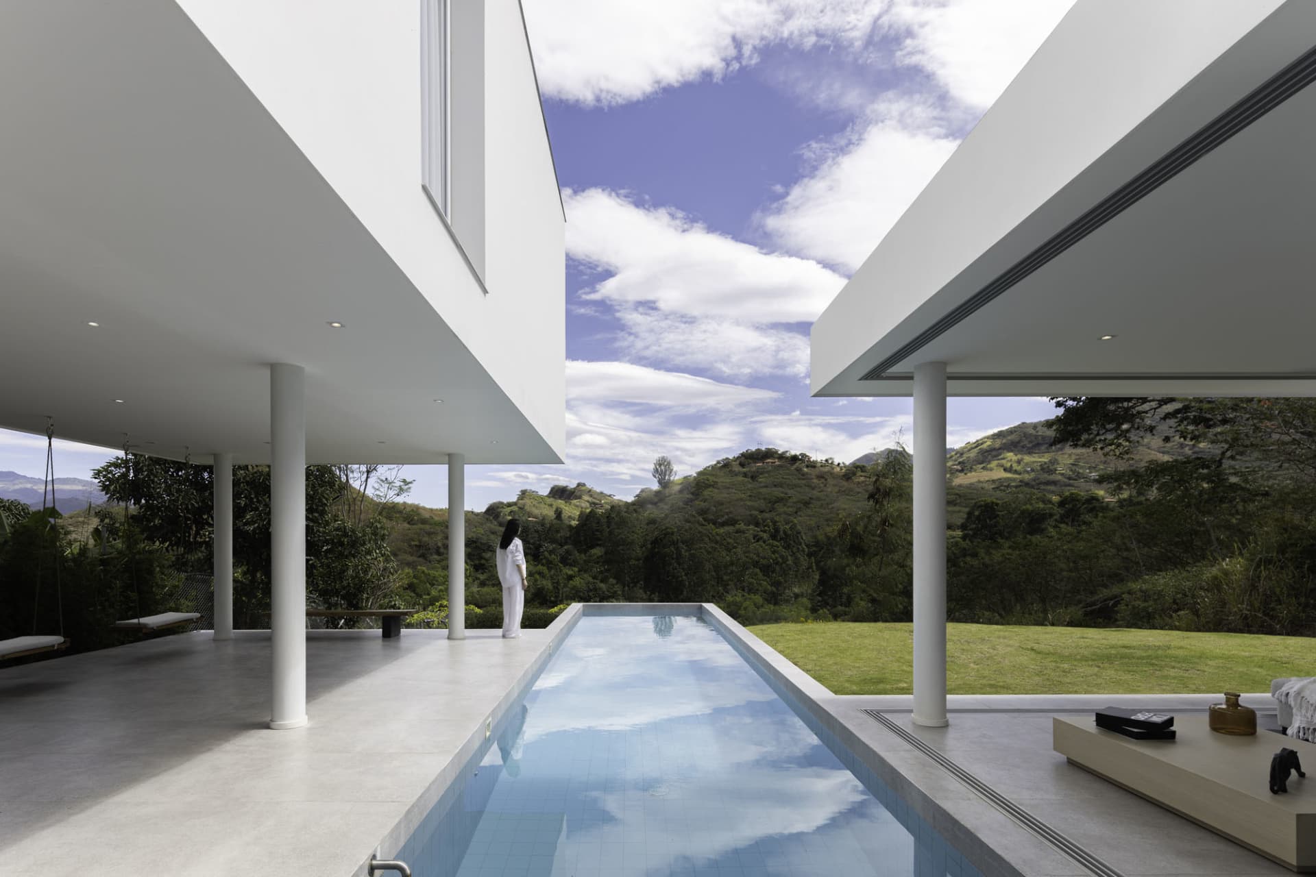 A modern poolhouse featuring concrete and glass materials with a swimming pool.