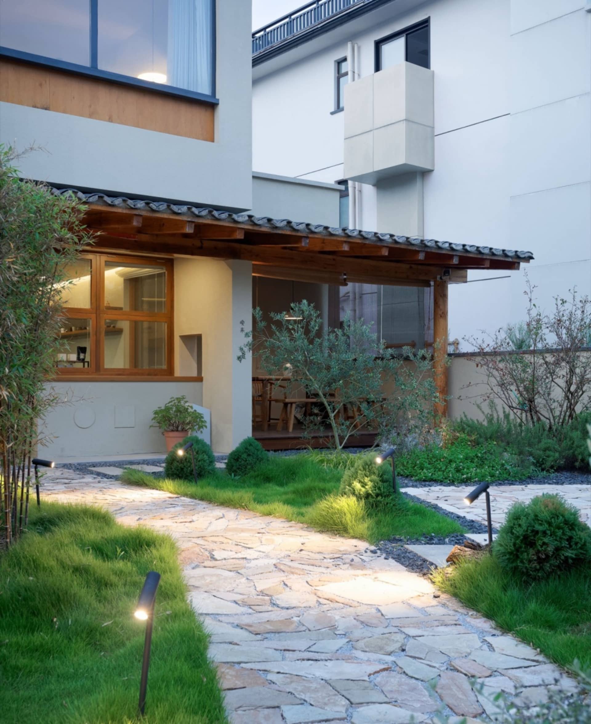 極簡住宅外觀,搭配石板步道與茂盛綠意。