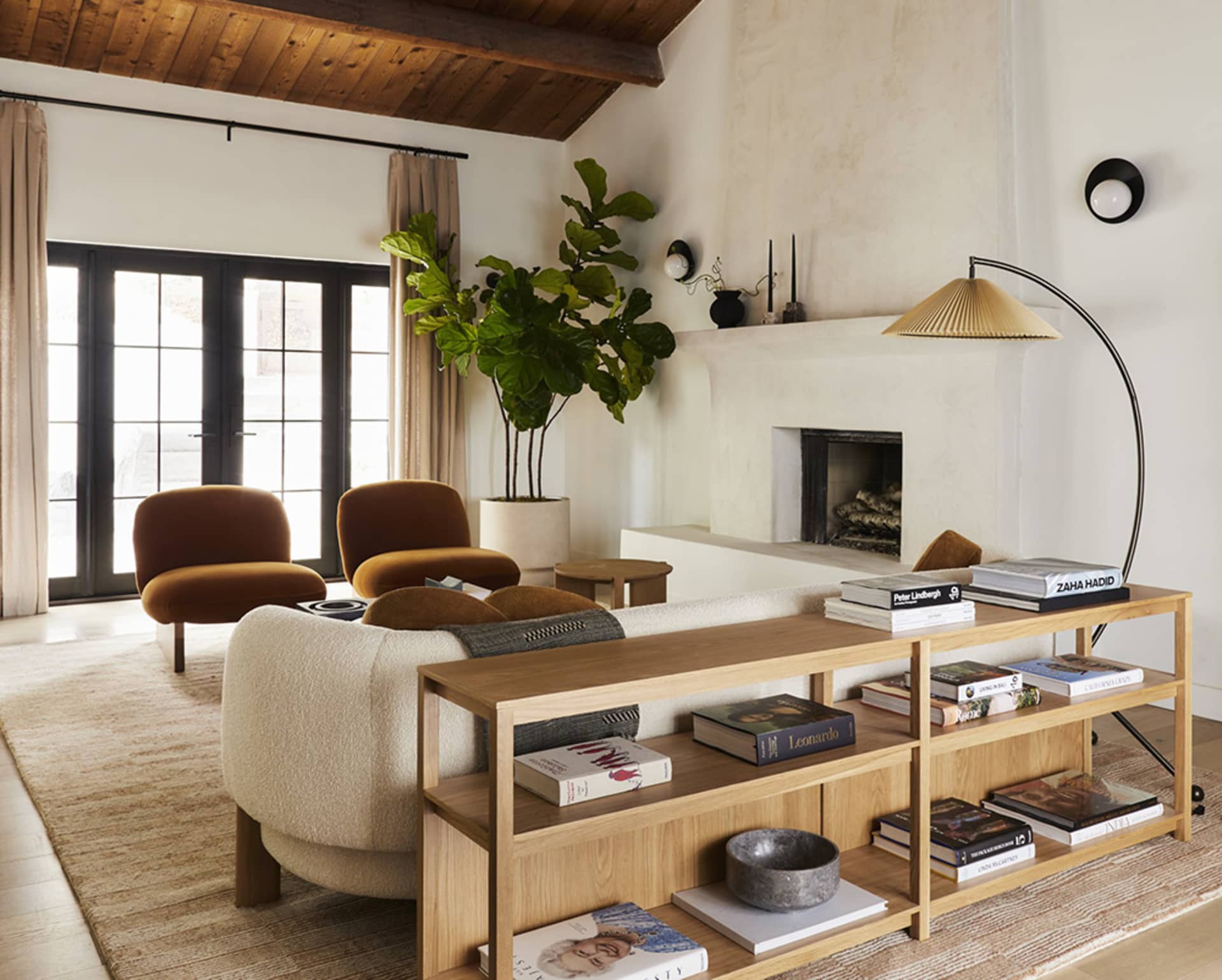 A modern living room featuring wooden furniture, a fireplace, and a potted plant.