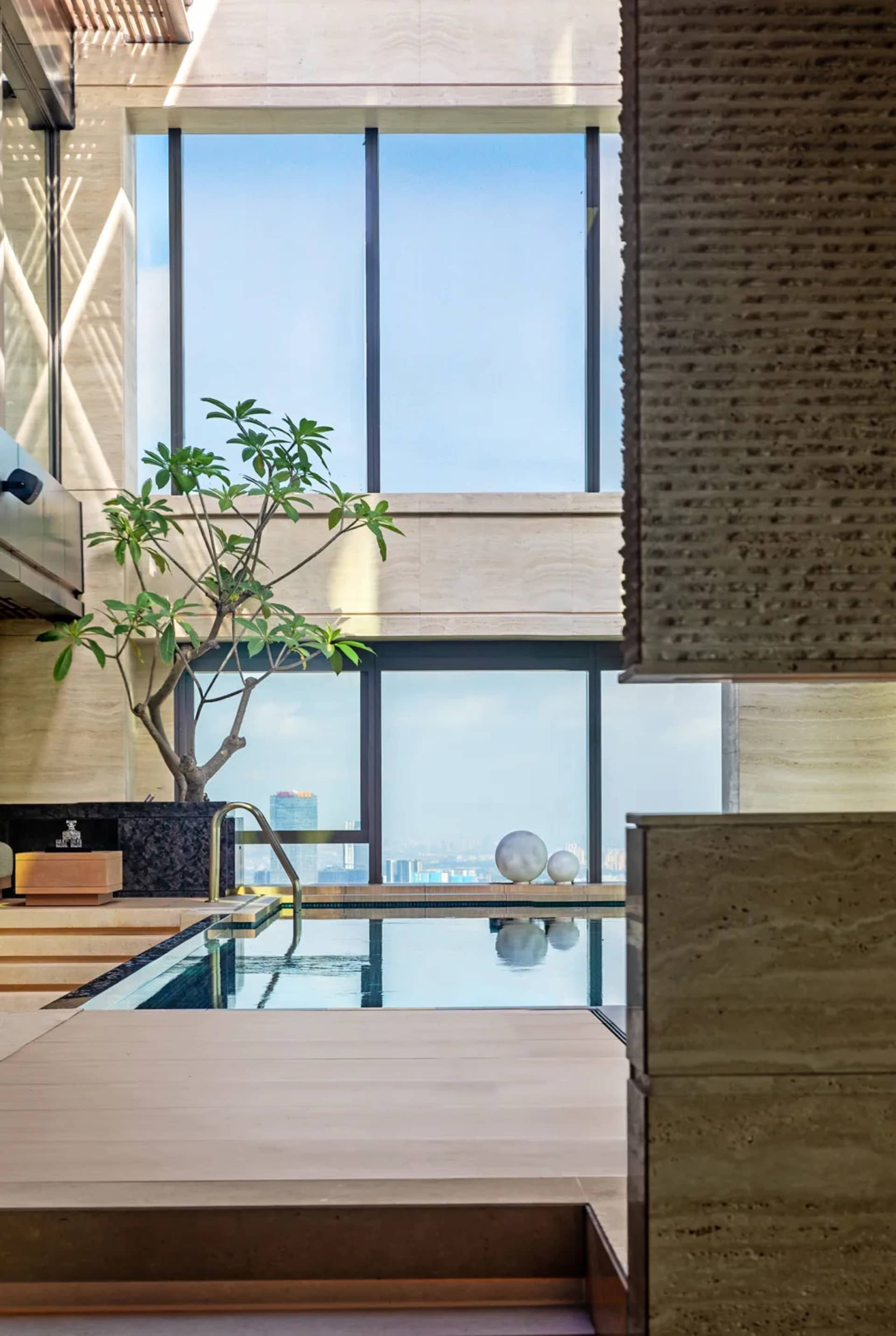 An elegant indoor swimming pool with modern design elements, including concrete, glass, and stainless steel.