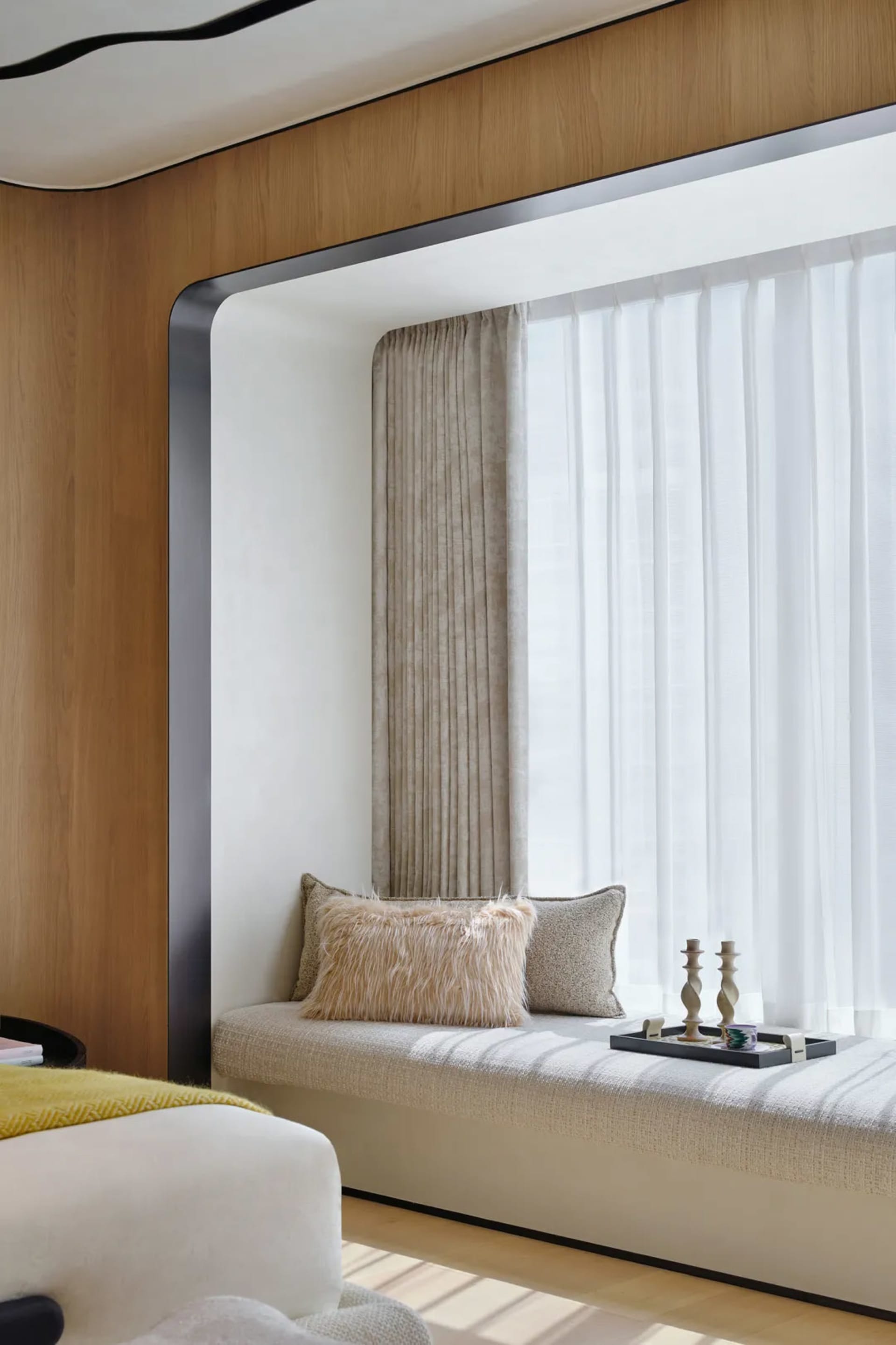 A modern window seat with plush cushions and fabric curtains.