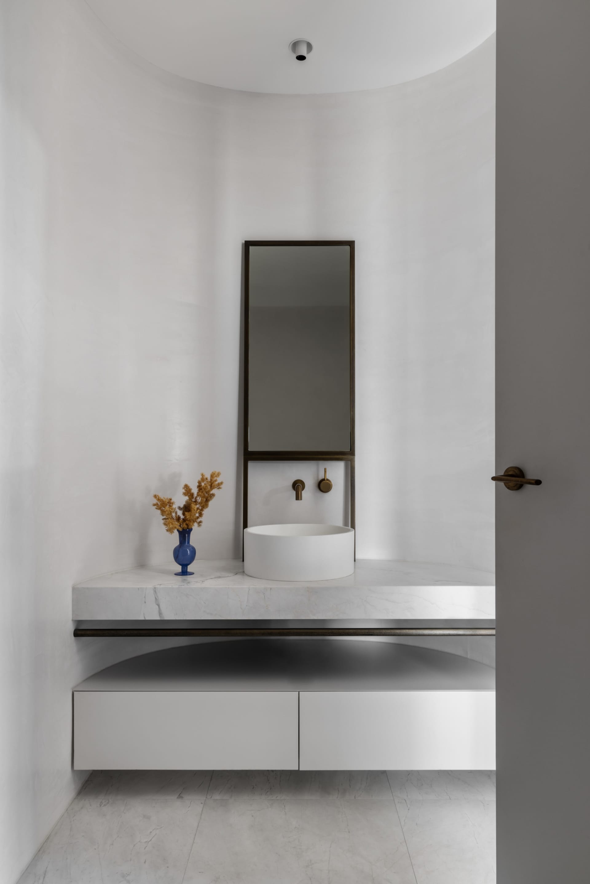 A minimalist bathroom with a marble sink, counter, and mirror.