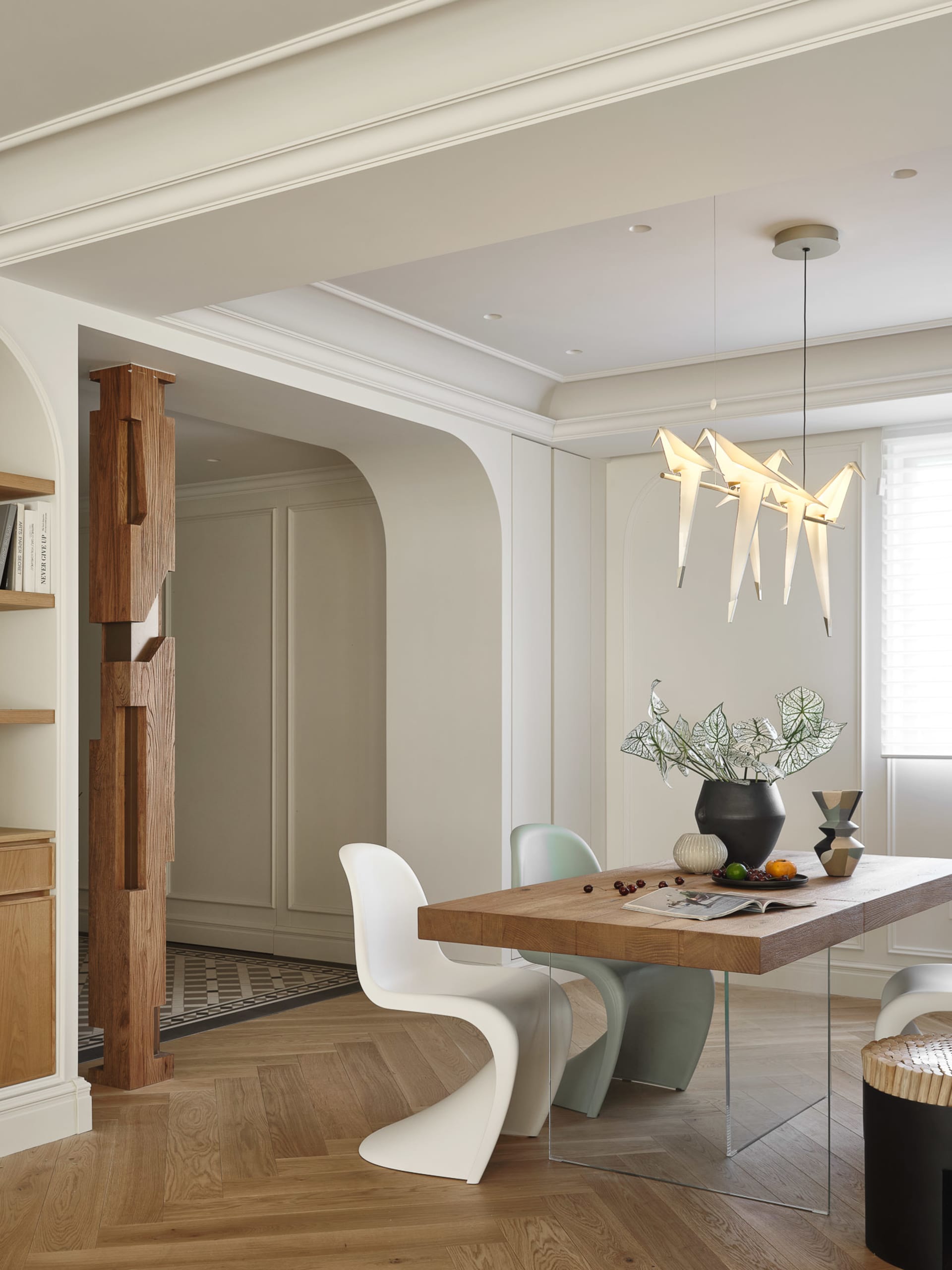 A modern dining room with a wooden table and chairs, featuring contemporary lighting and decor.