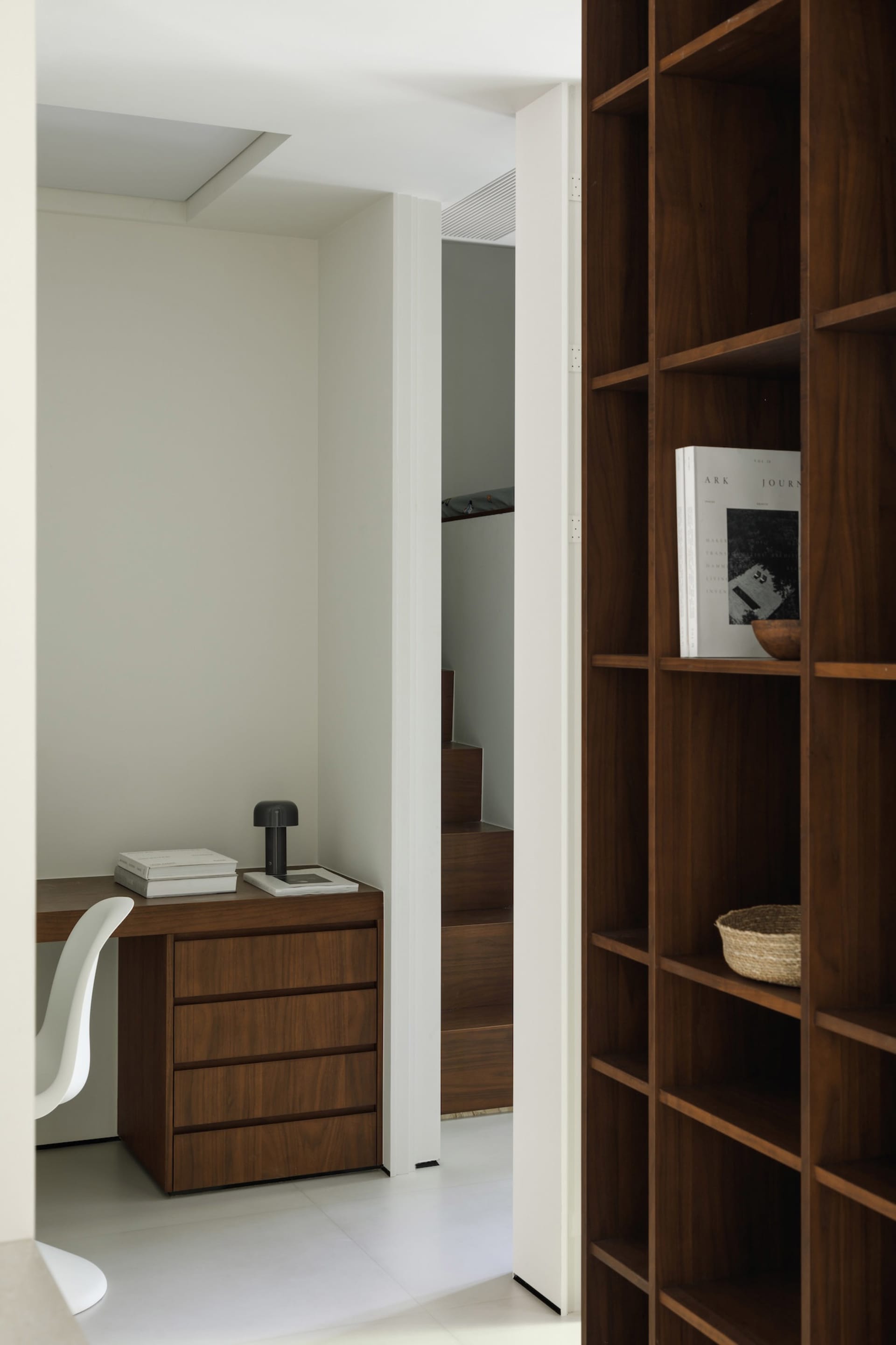 A modern interior space featuring a wooden bookshelf and white furniture.