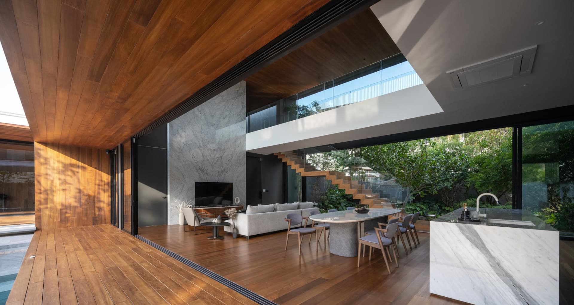 Modern living, dining, and kitchen space featuring wooden floors and marble elements.