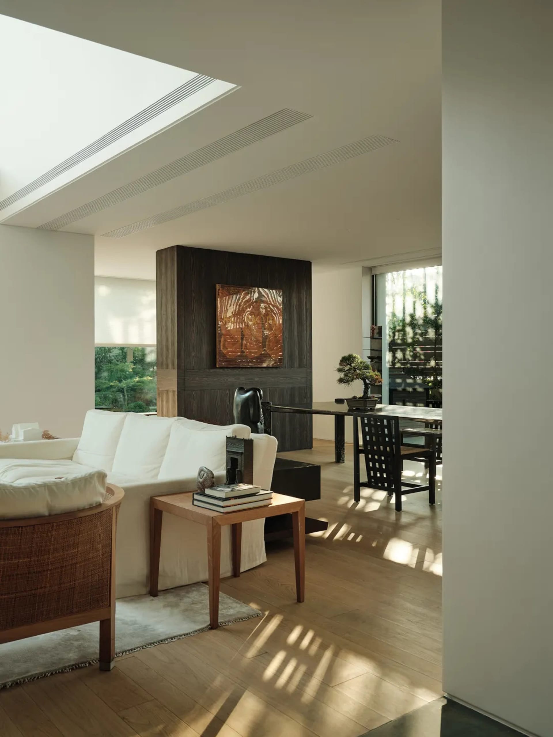 Modern living room featuring hardwood flooring, white sofas, and wooden side table with books and decorative items.