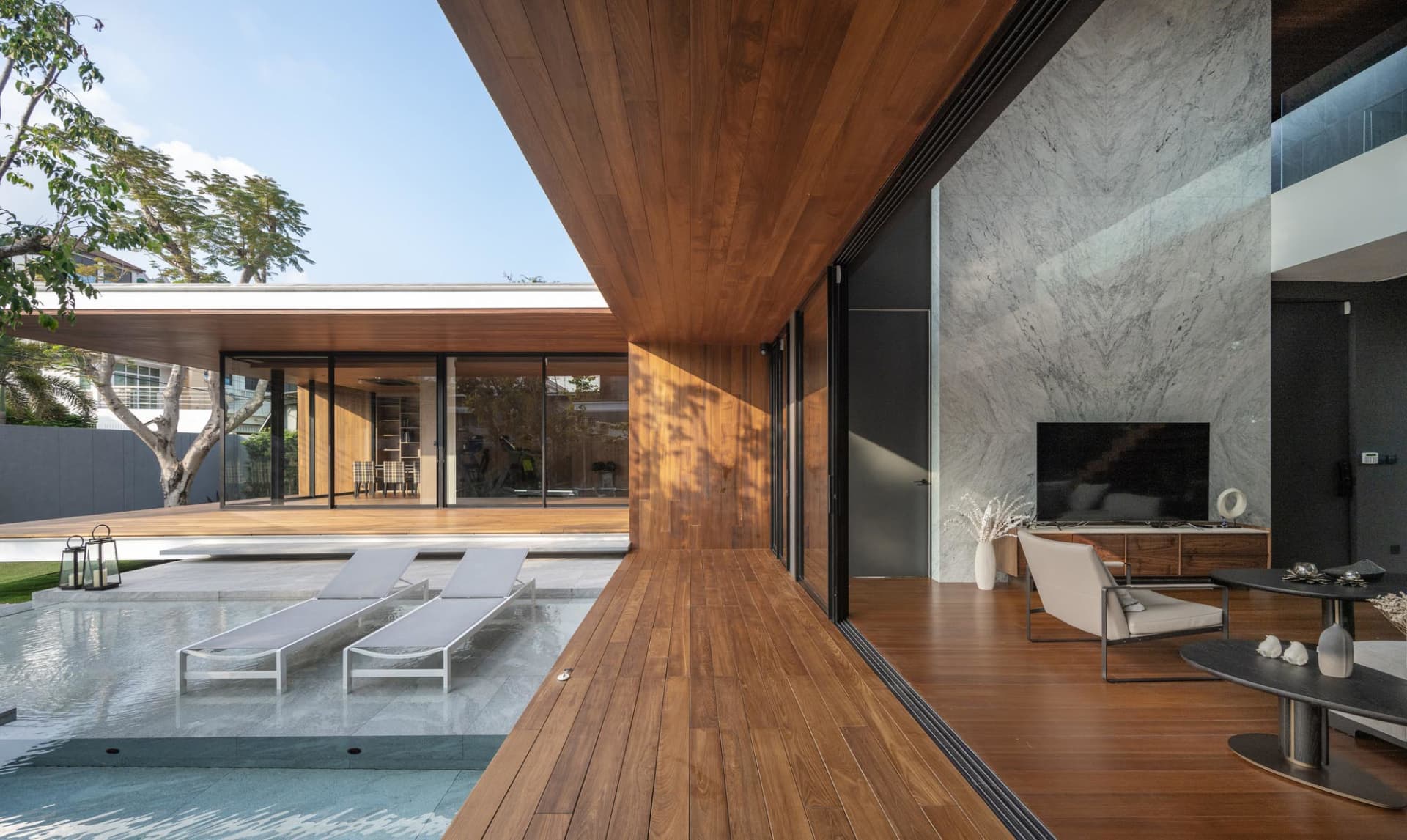 Modern living room with a wooden floor, lounge chairs, and a television.
