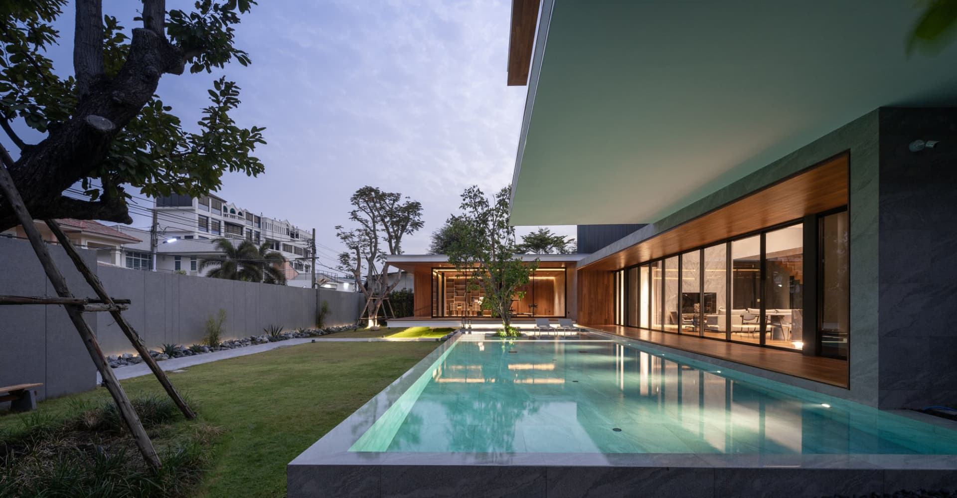 Modern residential exterior featuring a swimming pool surrounded by concrete and glass, designed for relaxation and style.