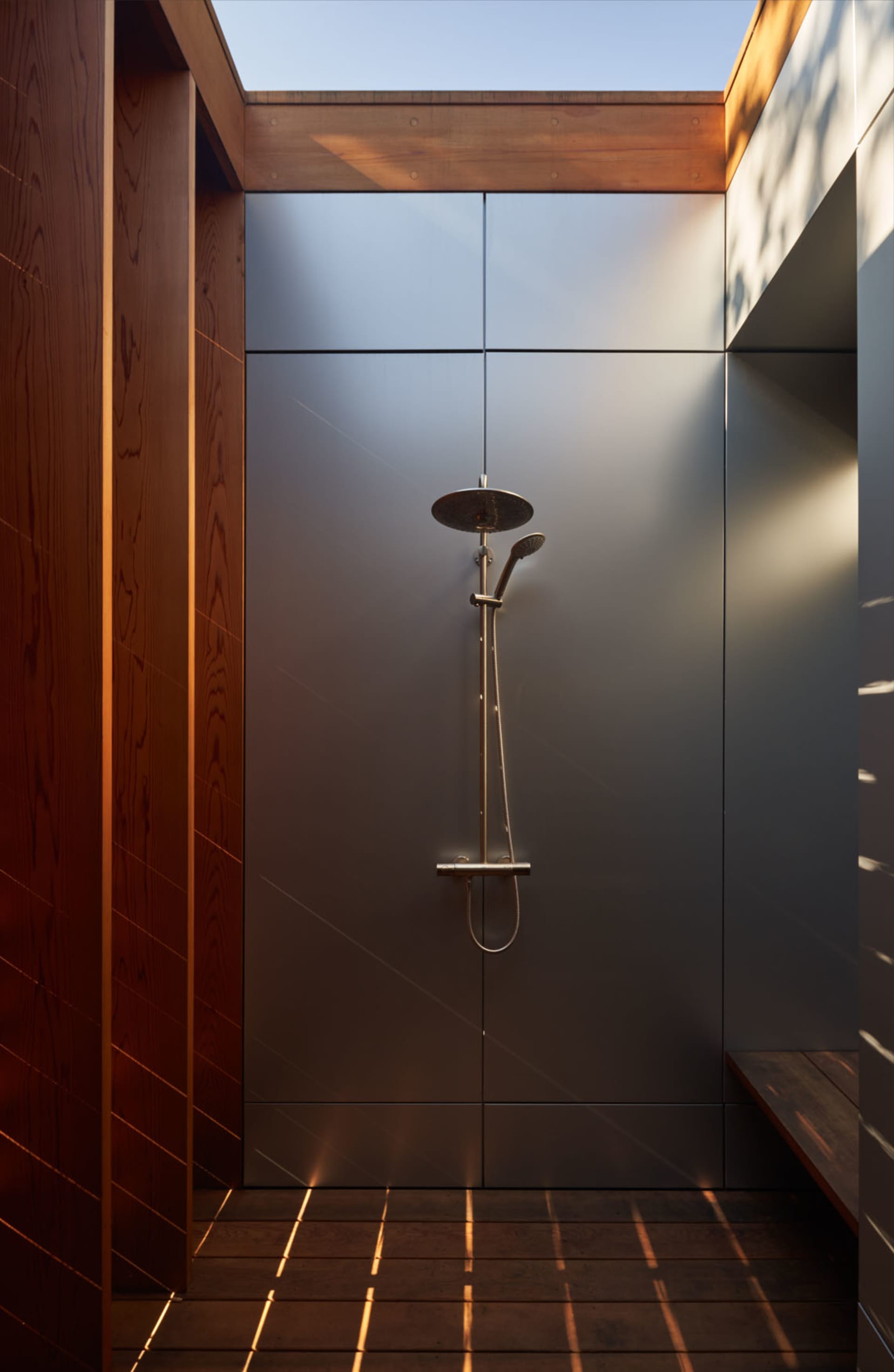 Modern minimalist bathroom with a glass shower enclosure, featuring sleek, stainless steel fixtures.
