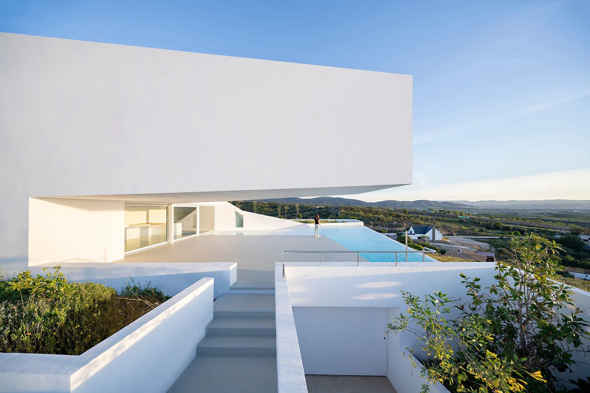 A modern residential architecture featuring a concrete structure and infinity pool overlooking scenic landscape.