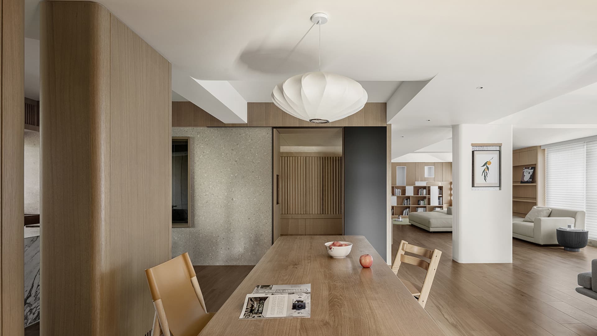 A modern minimalist interior featuring a wooden dining table with a concrete backdrop, and a hanging light fixture