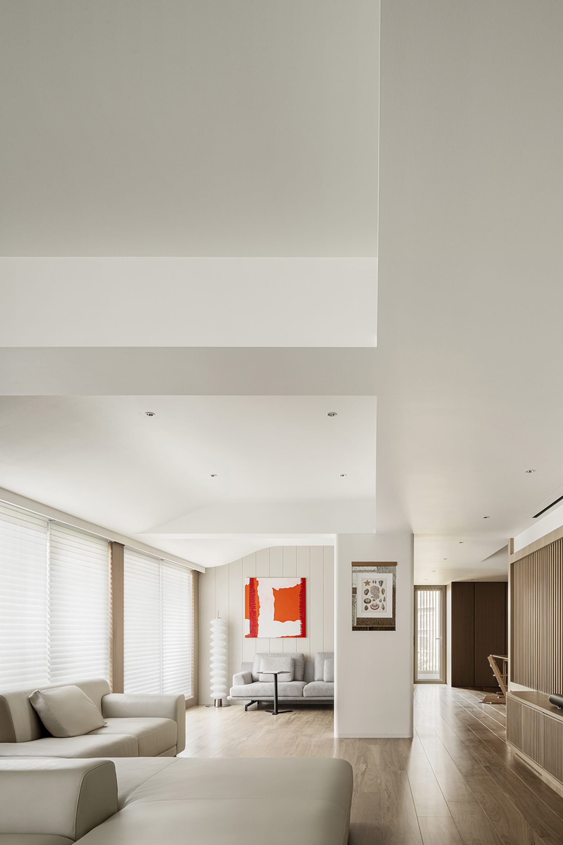A modern living room featuring minimalist design with neutral tones, white sofas, and wooden flooring.