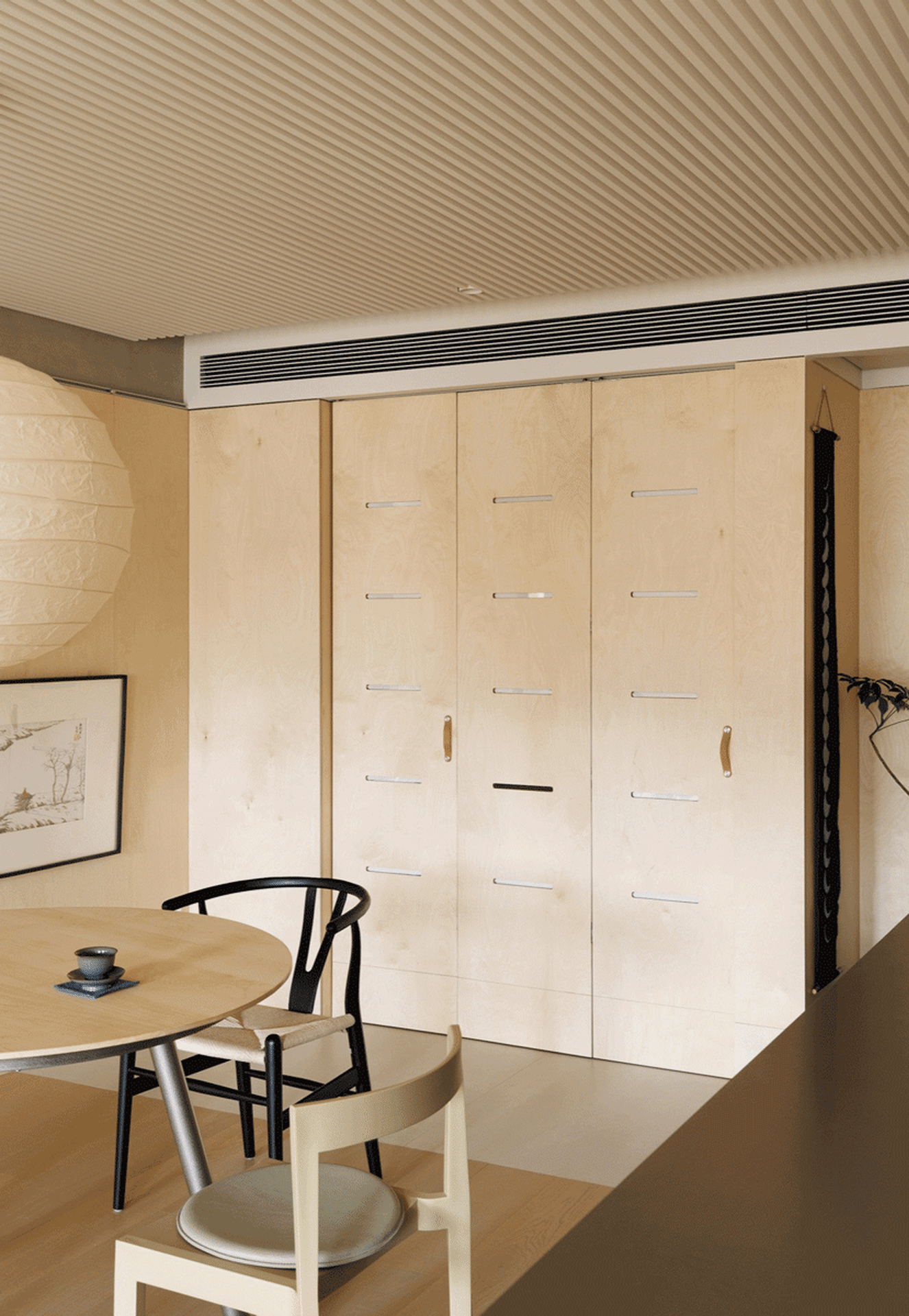 A modern minimalist kitchen with wooden cabinets and a dining table.