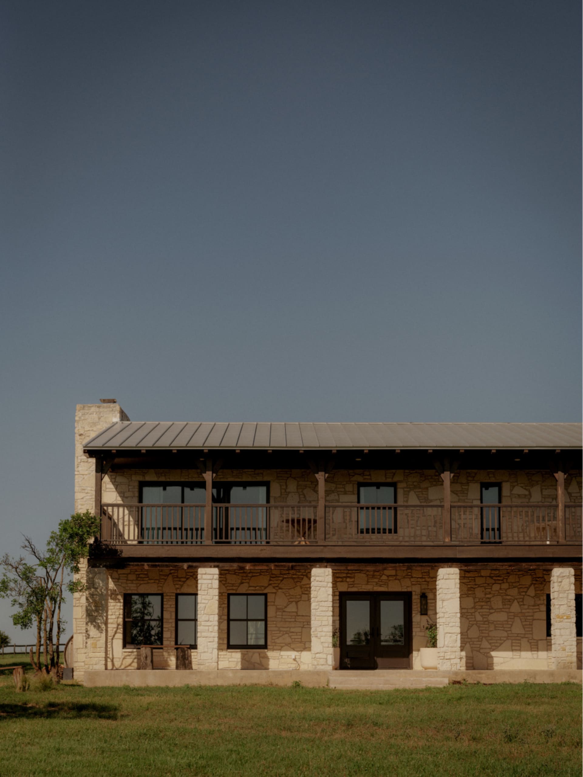 A two-story ranch house with a stone exterior and metal roof.