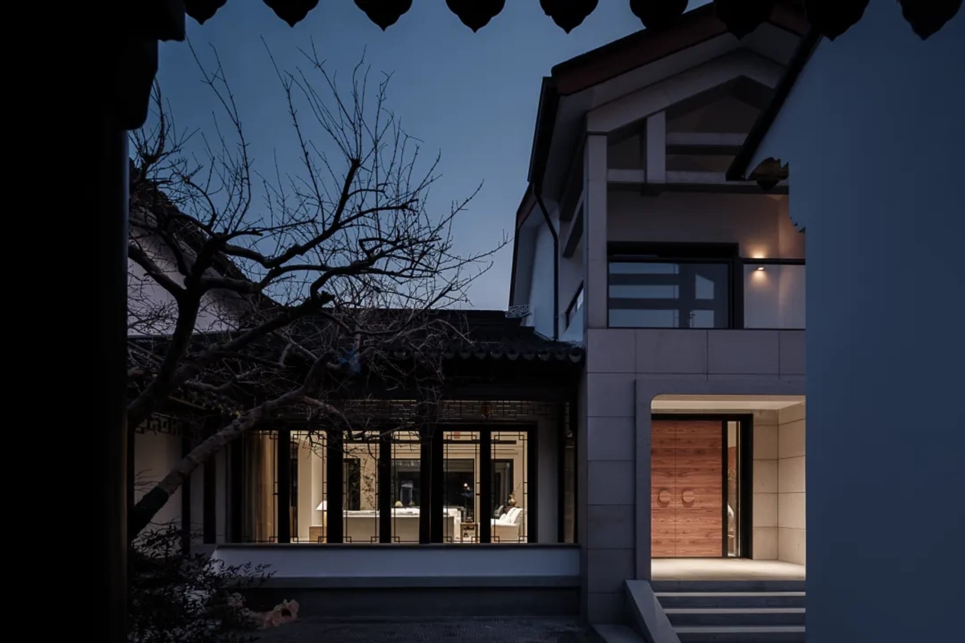 A modern residential exterior with concrete walls and wooden accents during dusk.